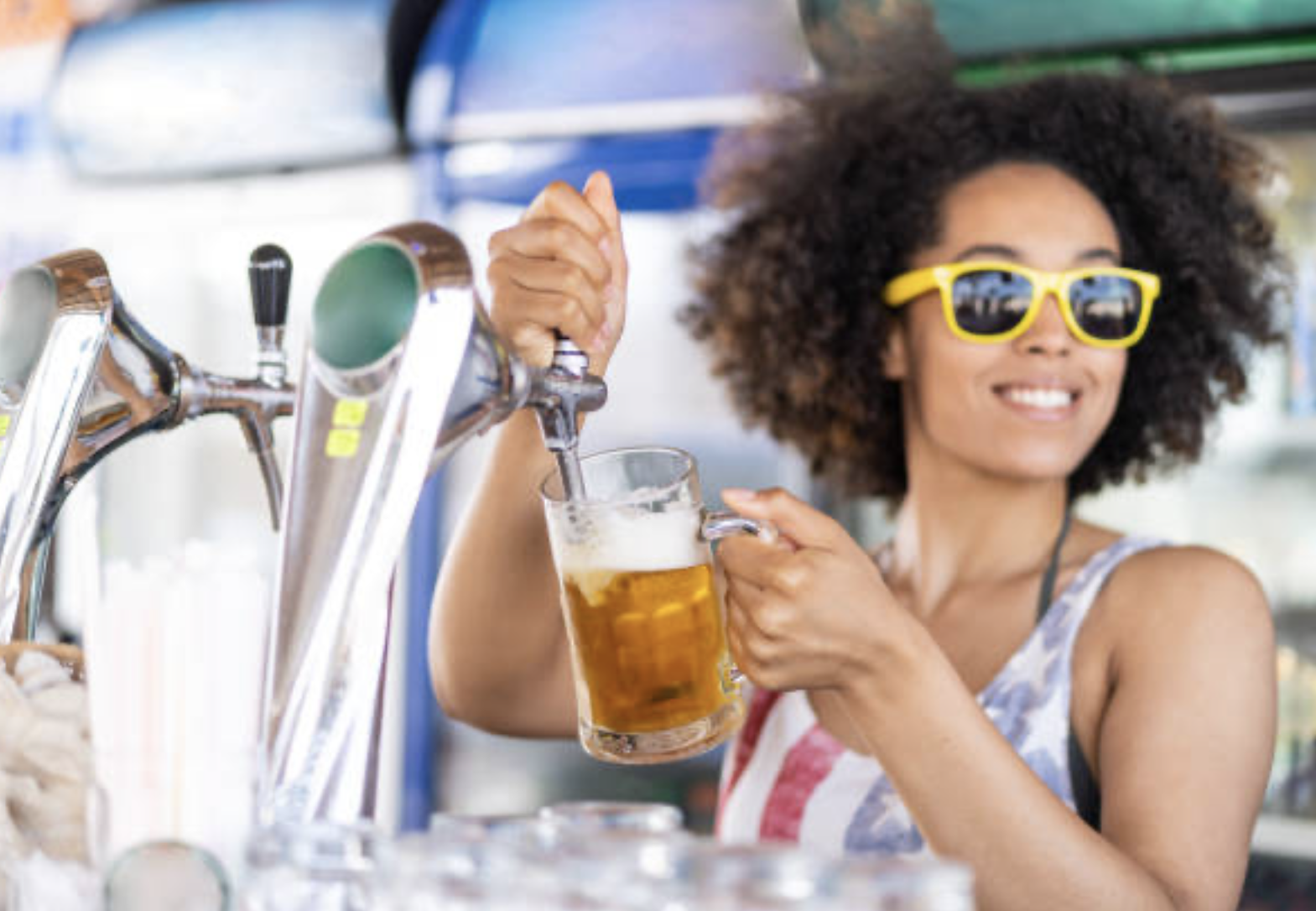A woman with having fun pouring a beer while bartending.