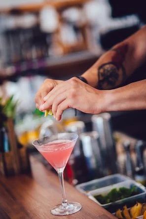 Bartender making a cocktail with a lime garnish.