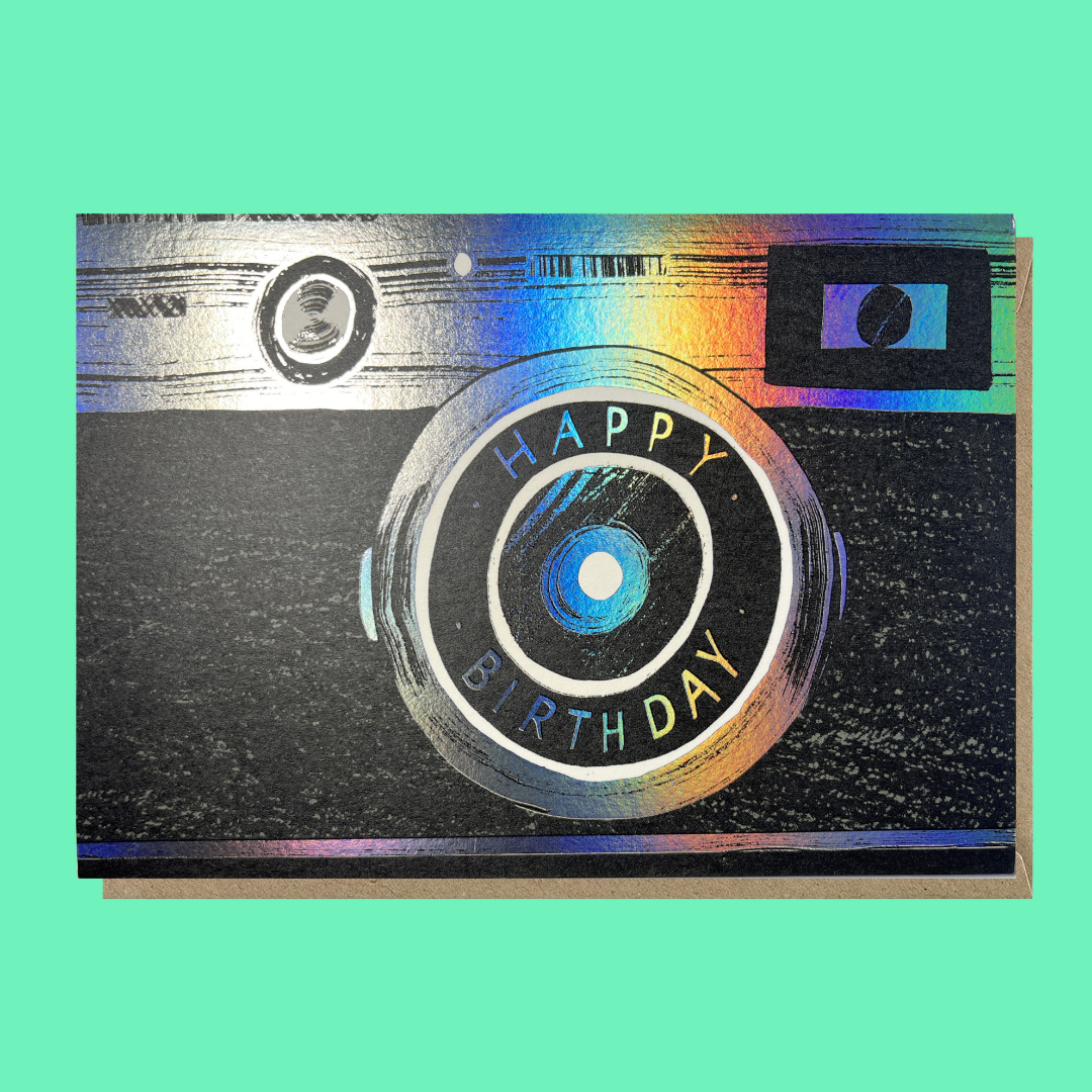 Colorful birthday greeting card with a camera illustration and the message 'HAPPY BIRTHDAY' inside the camera lens.