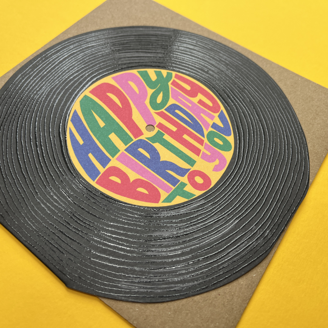Vinyl record with a colorful label that says 'Happy Birthday to You' on a yellow background.