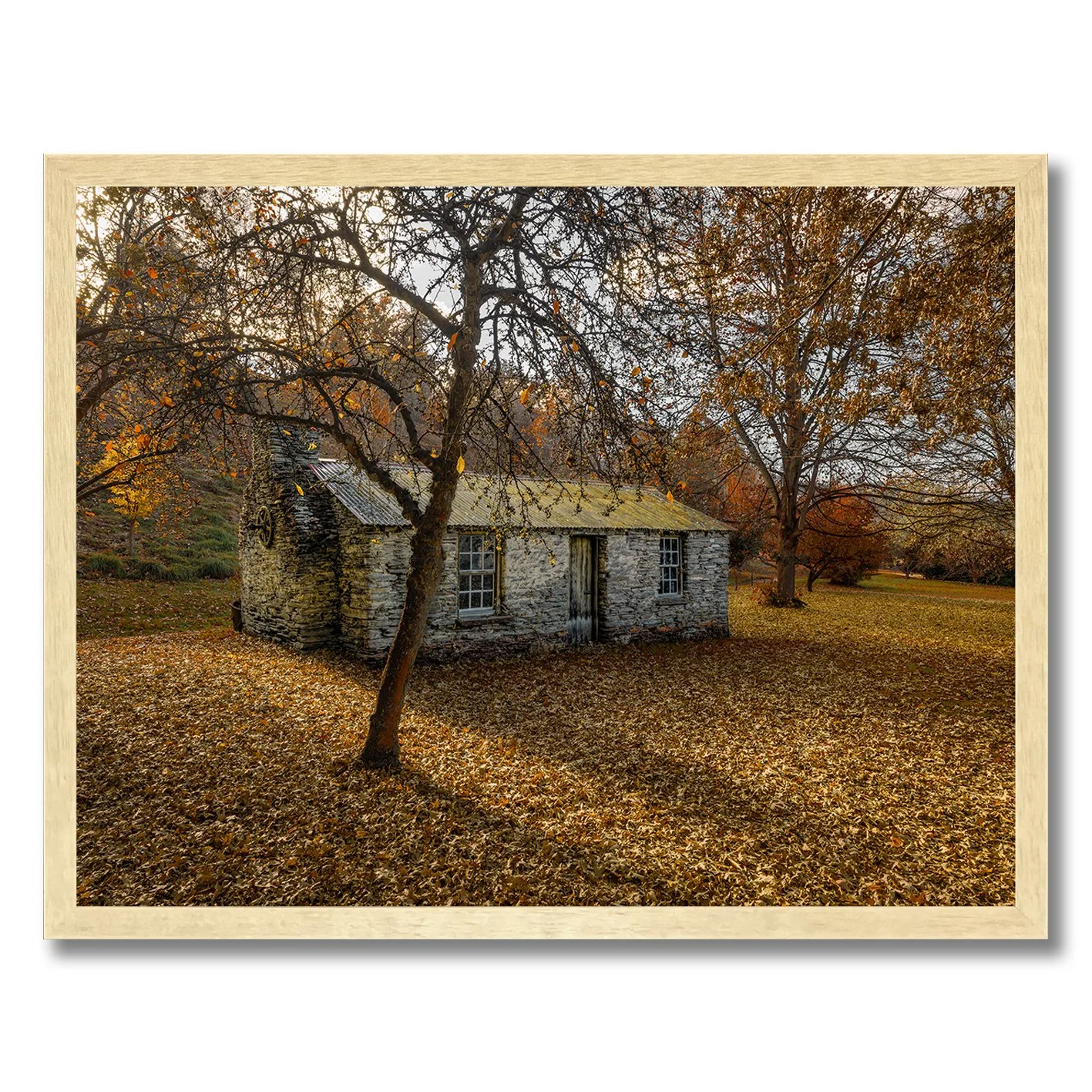 Stone cottage surrounded by autumn leaves and trees in a rural landscape photograph