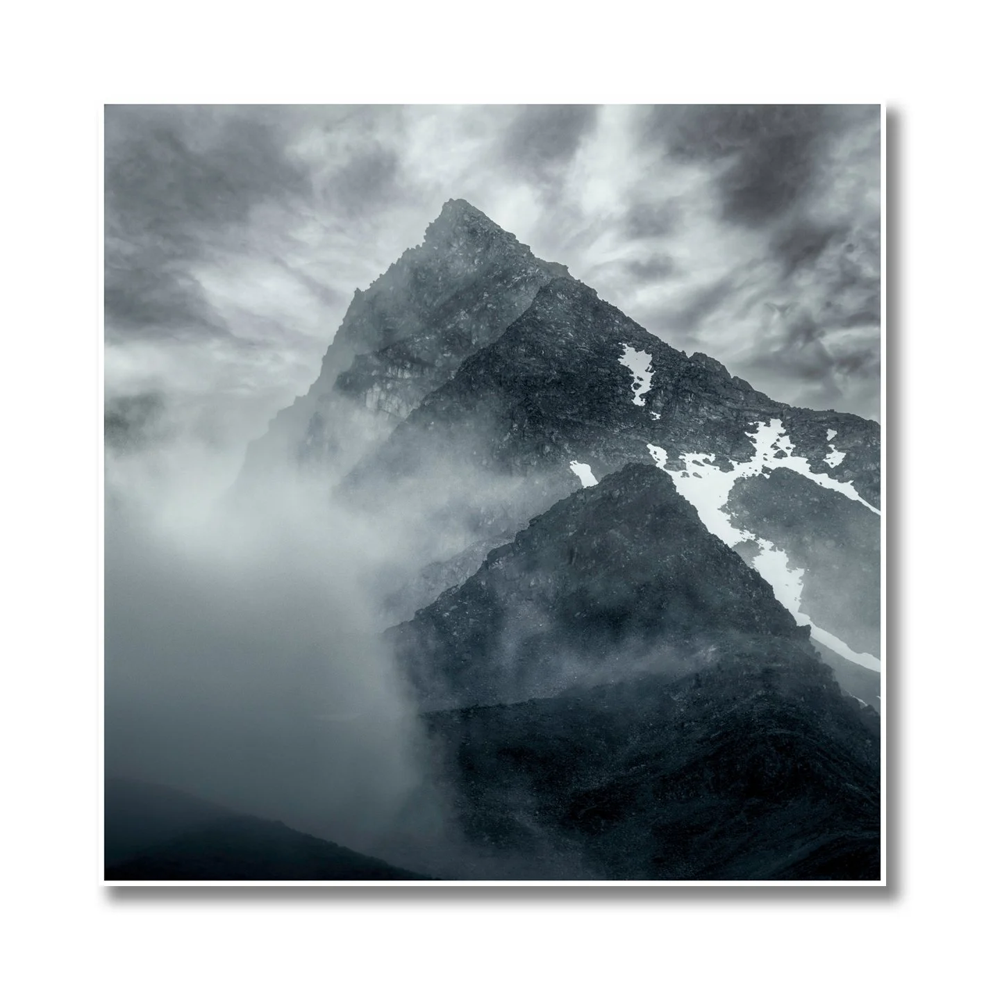 Mountain photograph emerging through mist and cloud with rugged alpine peak