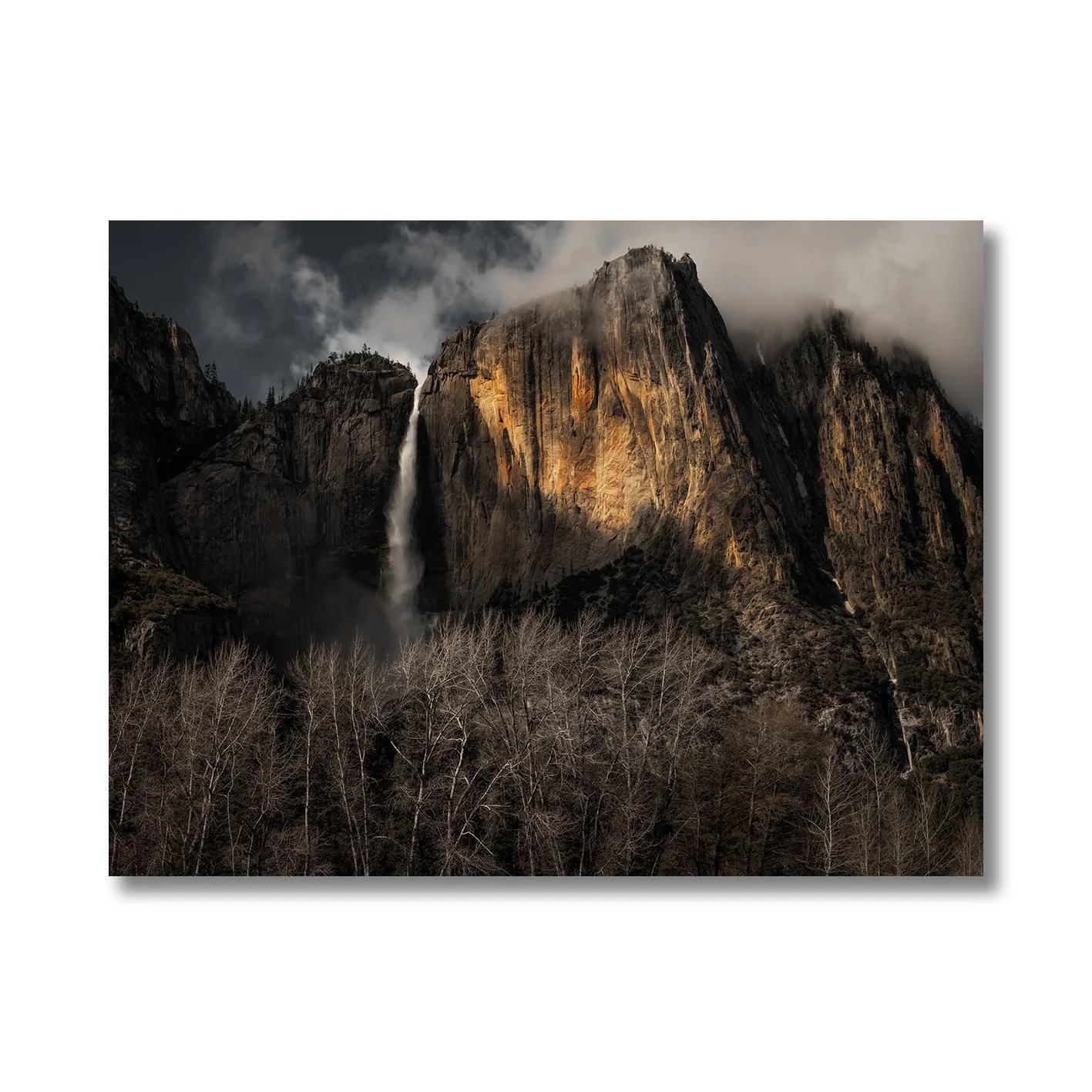 Yosemite Falls photograph with sunlit granite cliffs, mist and dark woodland in California