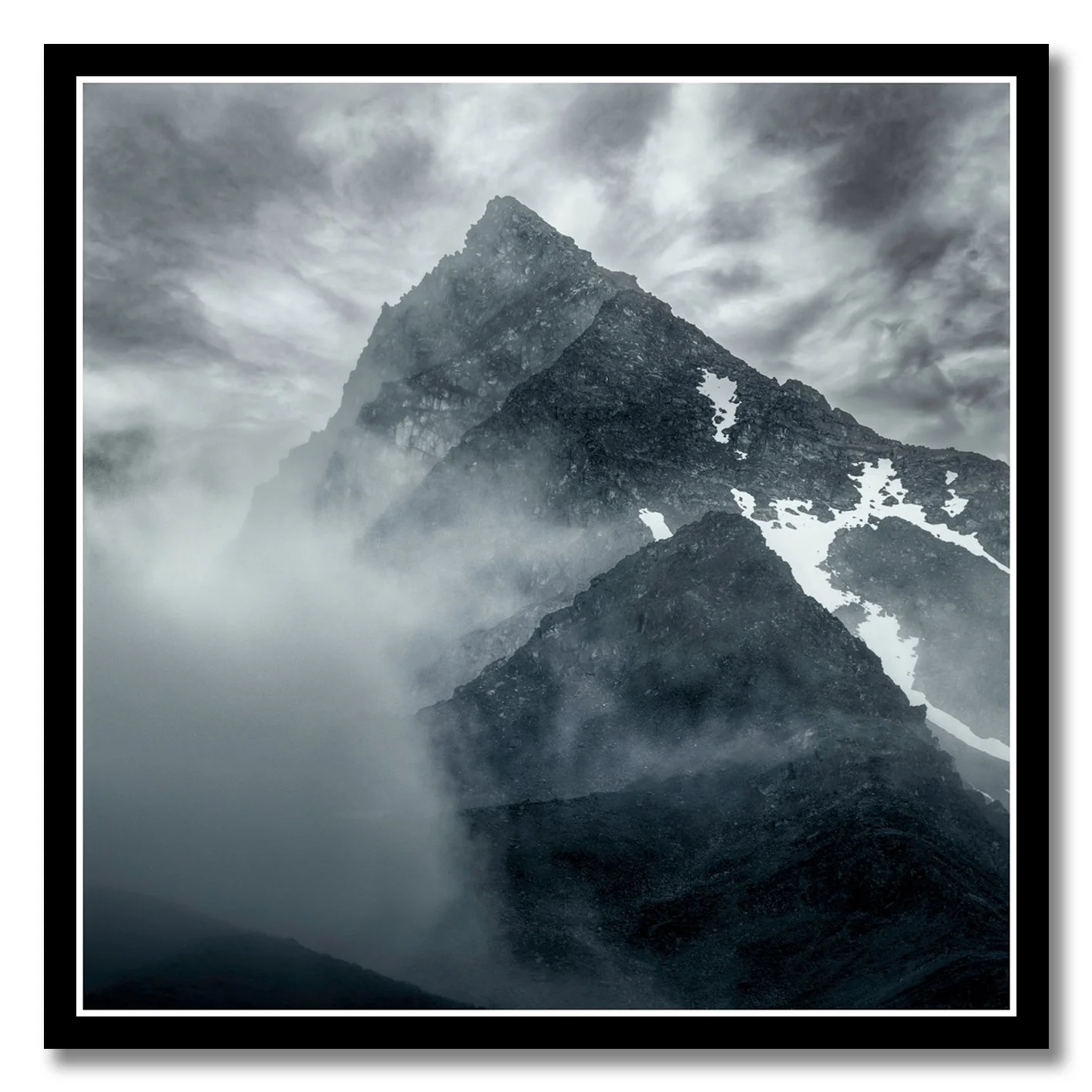 Mountain photograph emerging through mist and cloud with rugged alpine peak