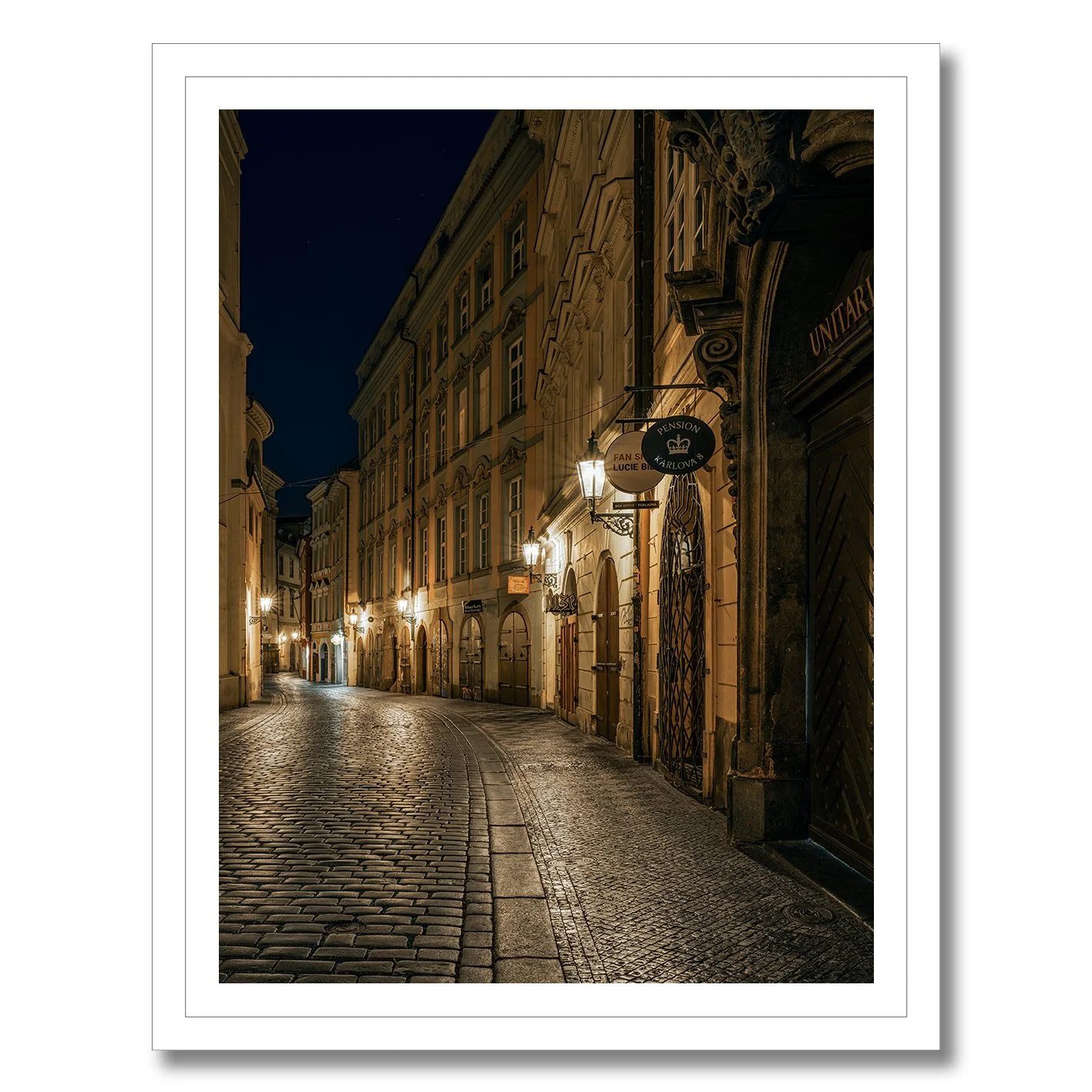 Night photograph of a quiet cobblestone street in Prague with warm lamps