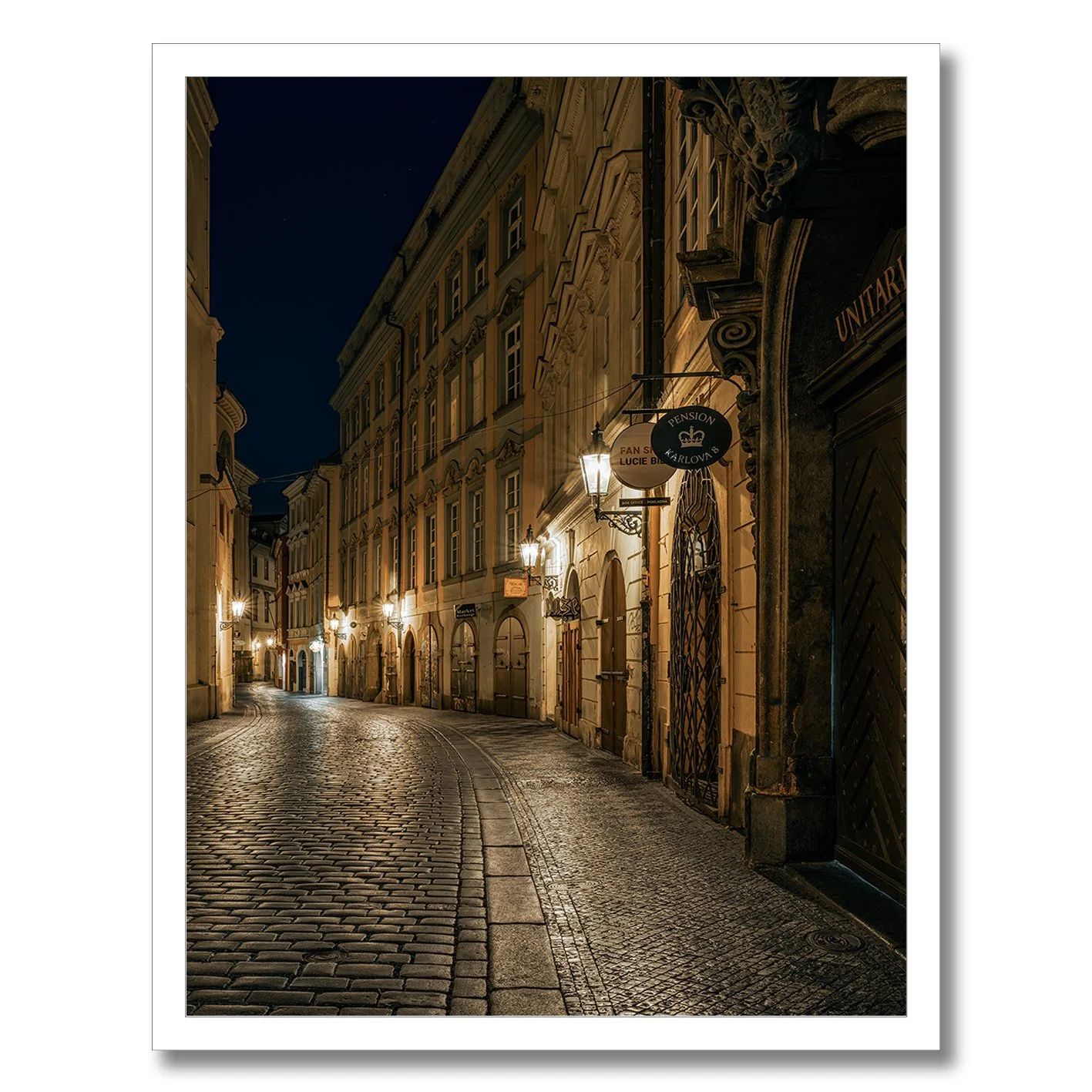 Night photograph of a quiet cobblestone street in Prague with warm lamps
