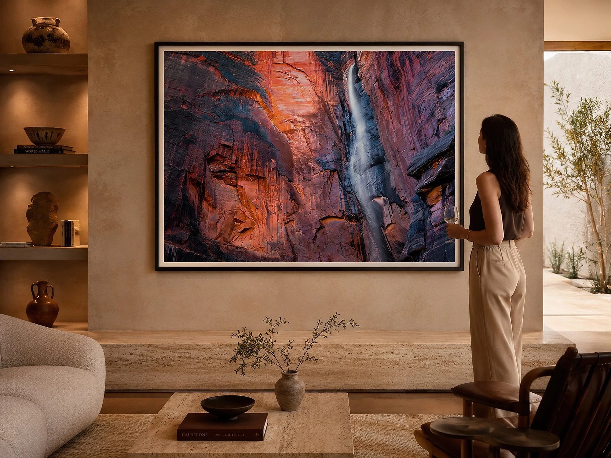 Framed Zion National Park waterfall photograph displayed in a warm contemporary living room with a woman standing nearby.