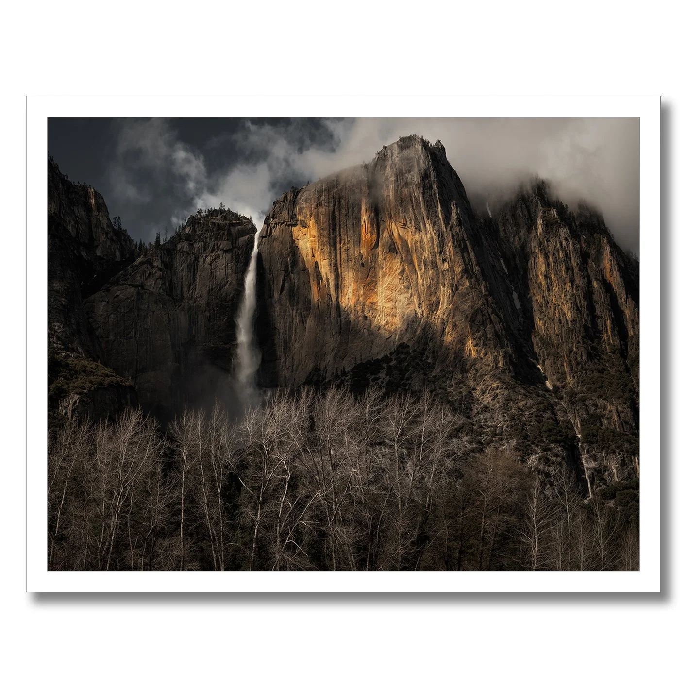 Yosemite Falls photograph with sunlit granite cliffs, mist and dark woodland in California