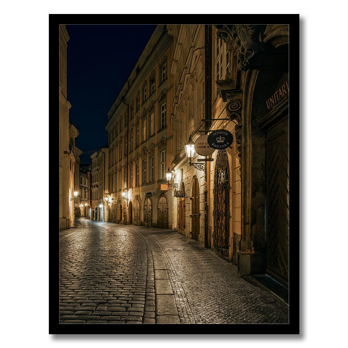 Night photograph of a quiet cobblestone street in Prague with warm lamps