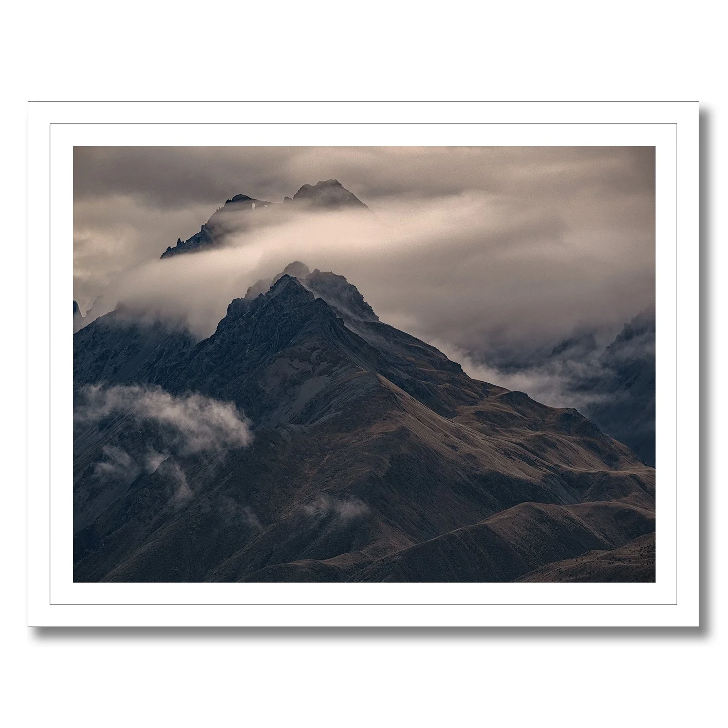 Moody mountain photograph with mist drifting across dark alpine ridges