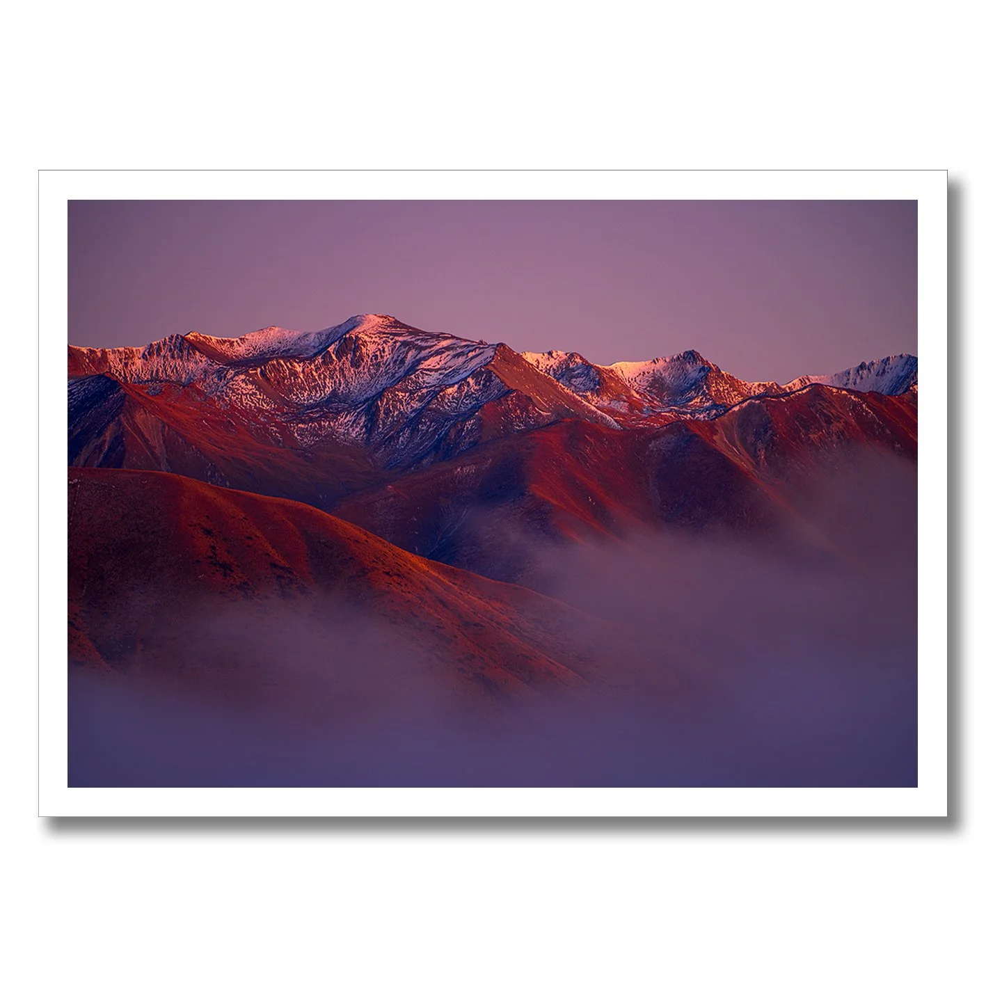 Mountain landscape photograph with alpenglow light on snowy peaks and misty valleys