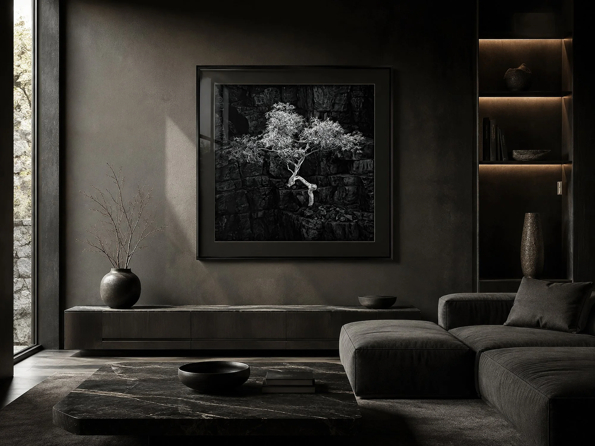 Framed black-and-white snow gum photograph with luminous silver foliage against dark rock in a moody minimalist living room with charcoal furnishings and natural window light, by Nick Psomiadis at NIKART Studio and Gallery