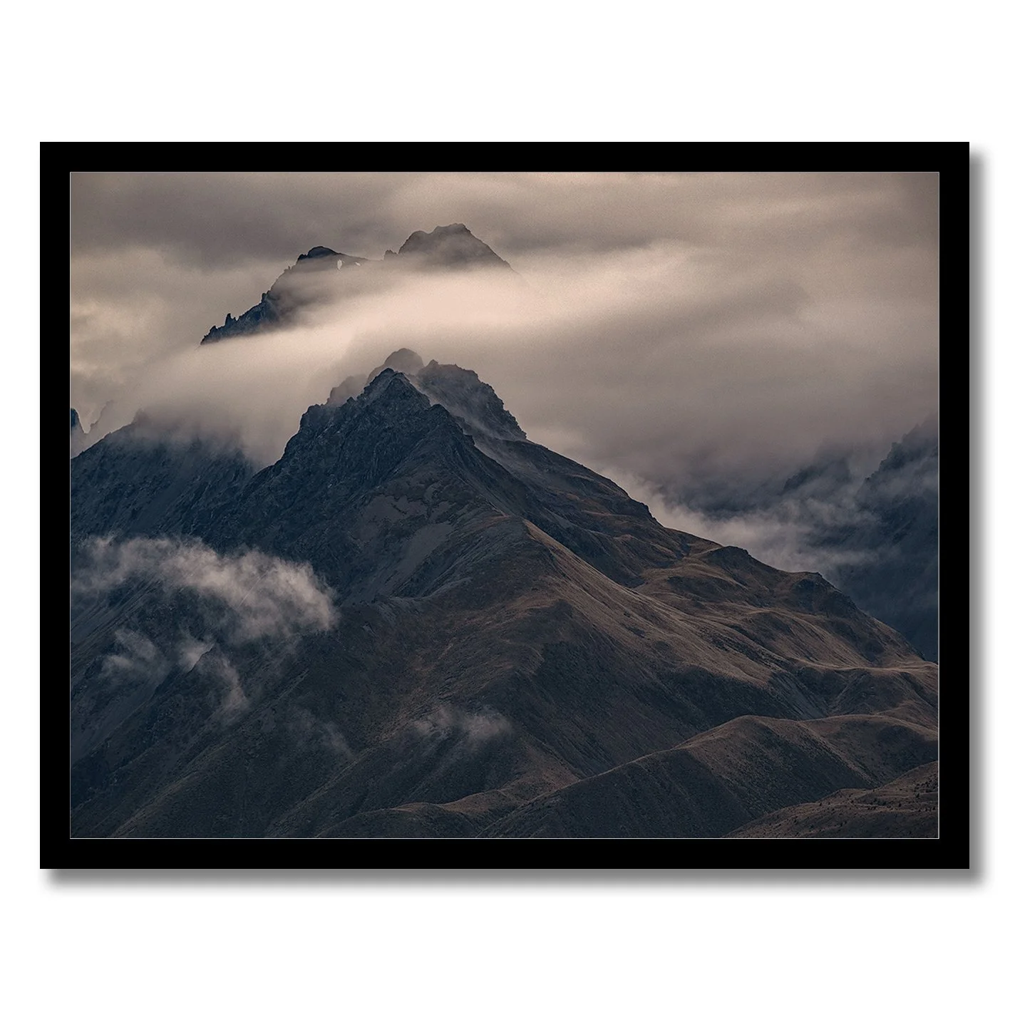 Moody mountain photograph with mist drifting across dark alpine ridges