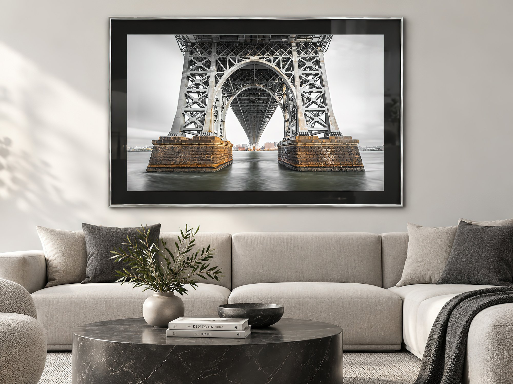 Architectural bridge photograph in a silver frame with black matting above a cream sofa in a bright contemporary lounge with soft natural light, by Nick Psomiadis at NIKART Studio and Gallery
