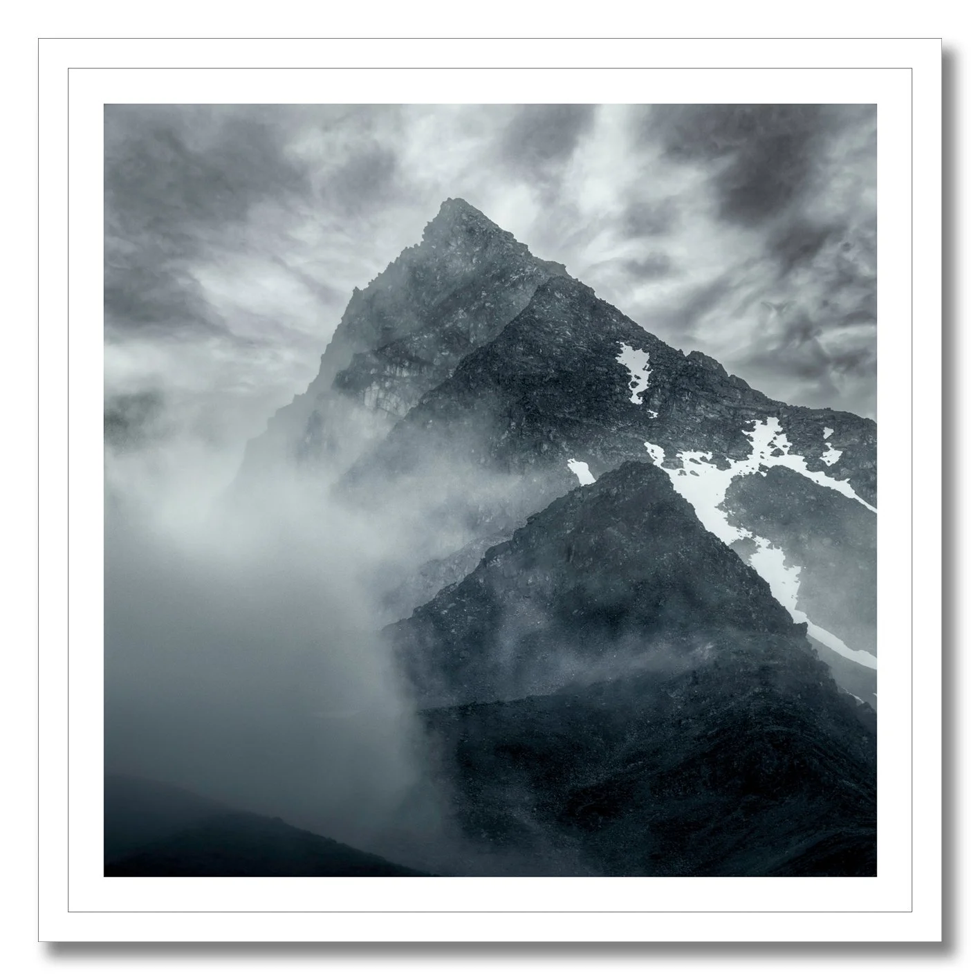 Mountain photograph emerging through mist and cloud with rugged alpine peak