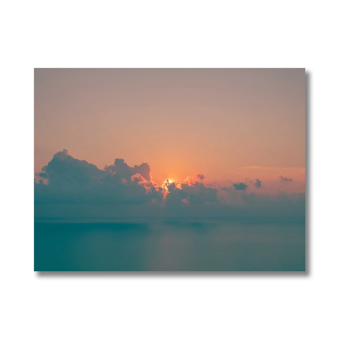 Sunrise seascape photograph with glowing horizon and soft clouds over calm ocean