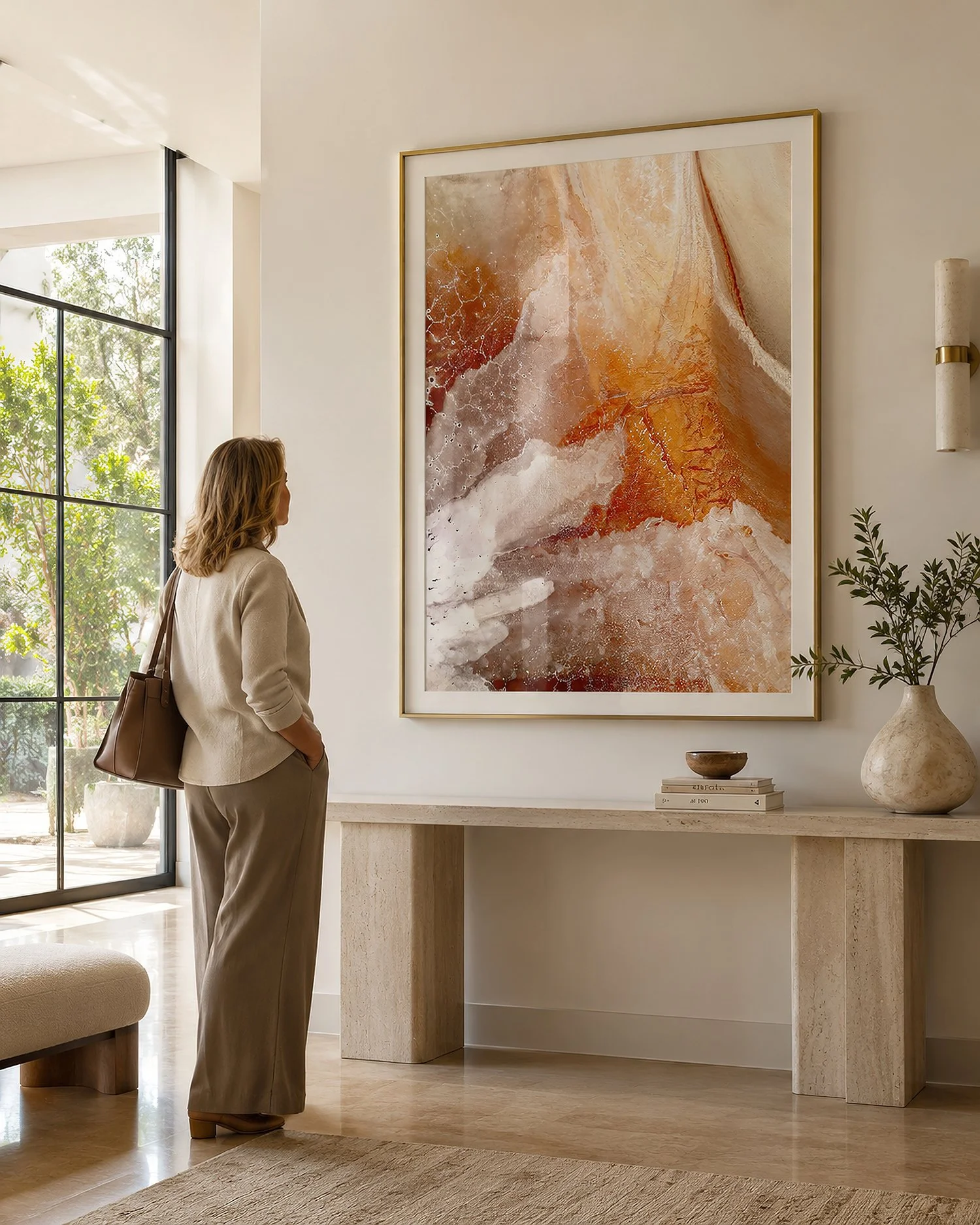 Bright contemporary entryway with a woman viewing a gold-framed orange and cream abstract photograph by Nick Psomiadis at NIKART Studio and Gallery