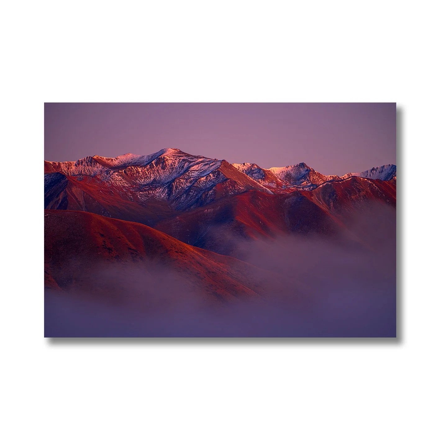 Mountain landscape photograph with alpenglow light on snowy peaks and misty valleys