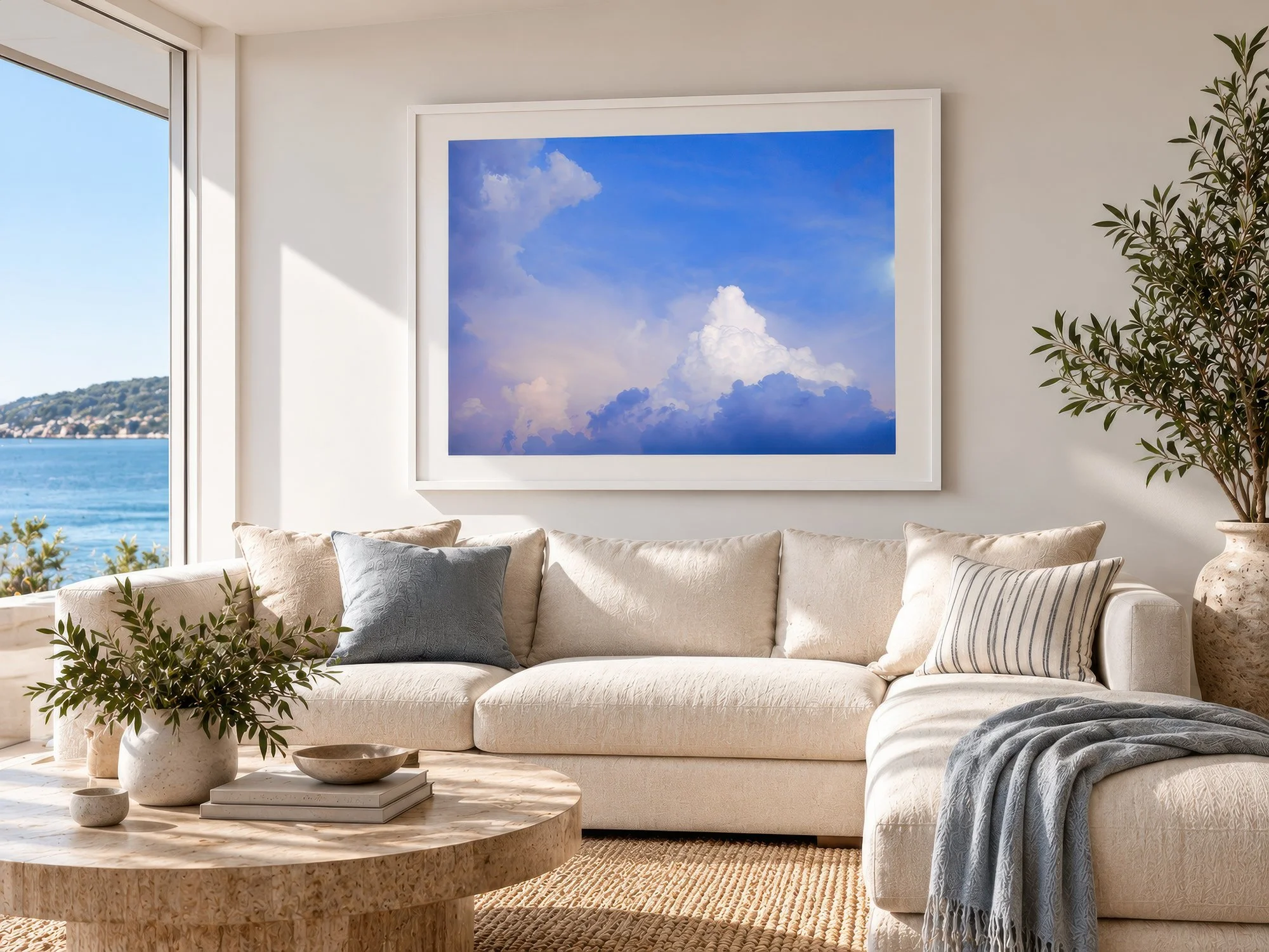 Blue and lavender cloudscape photograph in a white matted frame above a cream sofa in a coastal lounge, by Nick Psomiadis at NIKART Studio and Gallery
