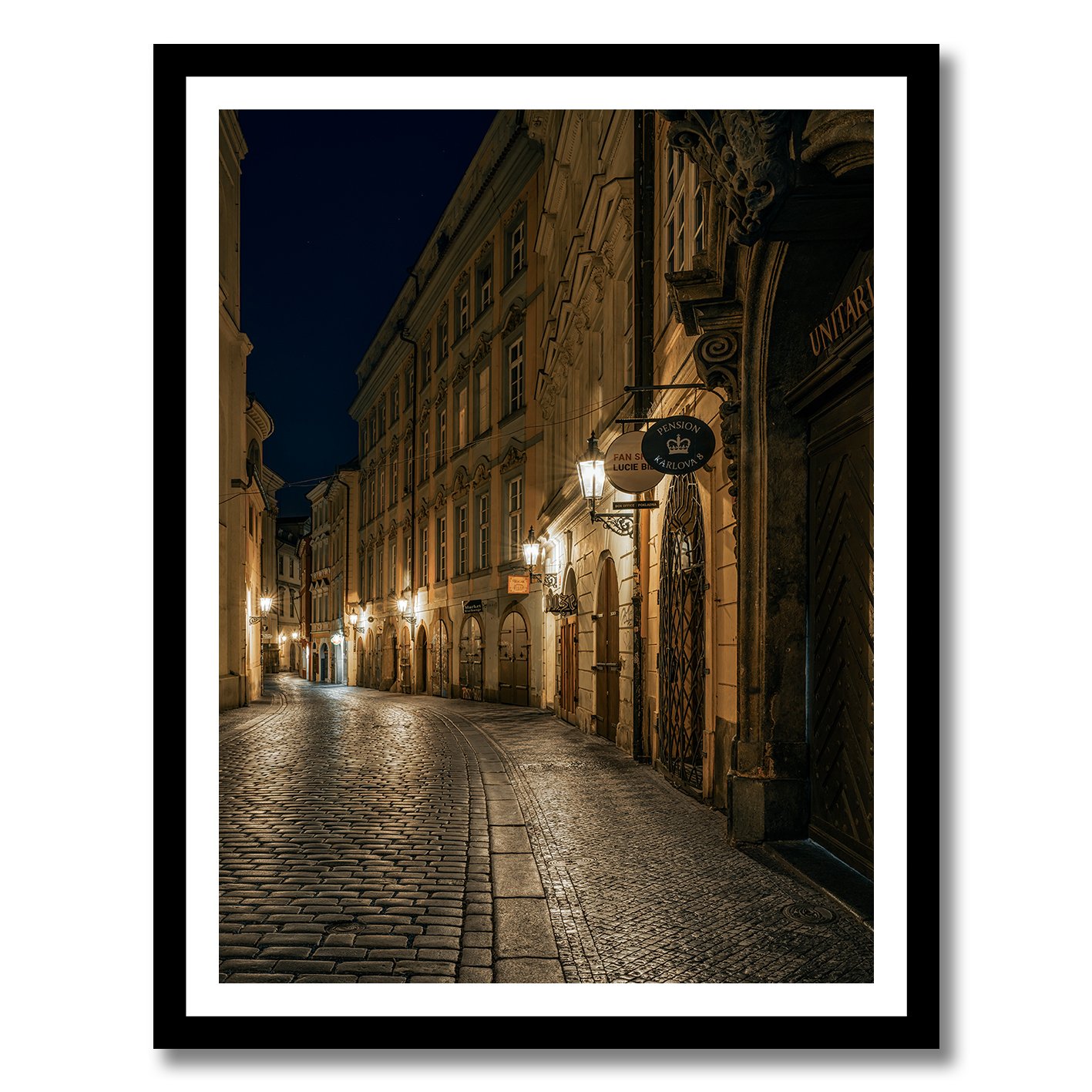 Night photograph of a quiet cobblestone street in Prague with warm lamps