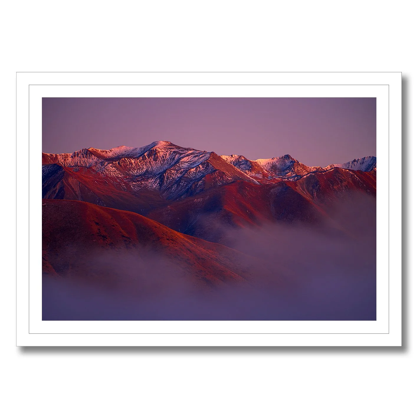 Mountain landscape photograph with alpenglow light on snowy peaks and misty valleys