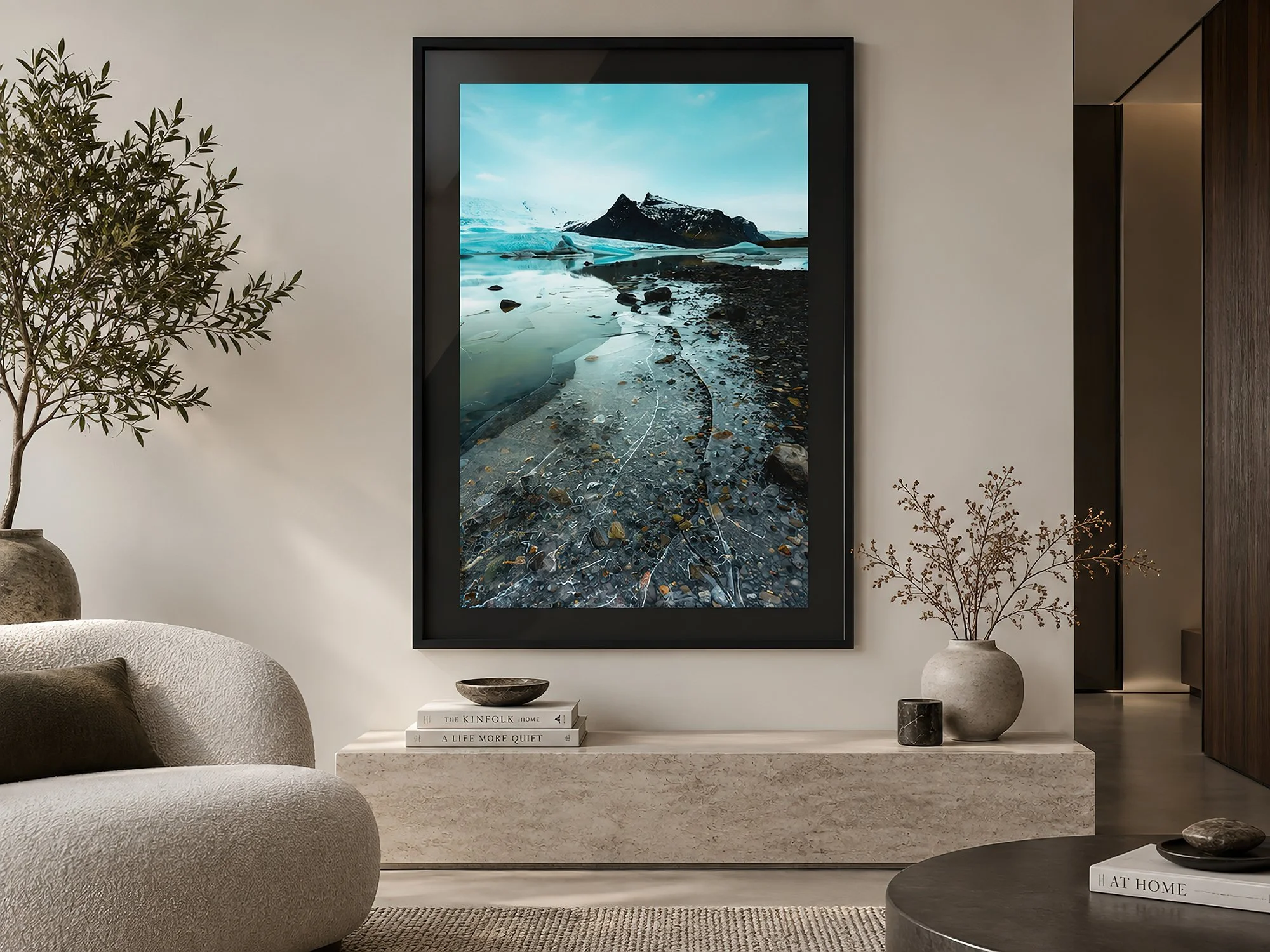 Icelandic glacier lagoon photograph with turquoise ice, dark mountain peaks and cracked shoreline ice in a black frame with black mat, displayed in a minimalist neutral interior by Nick Psomiadis at NIKART Studio and Gallery