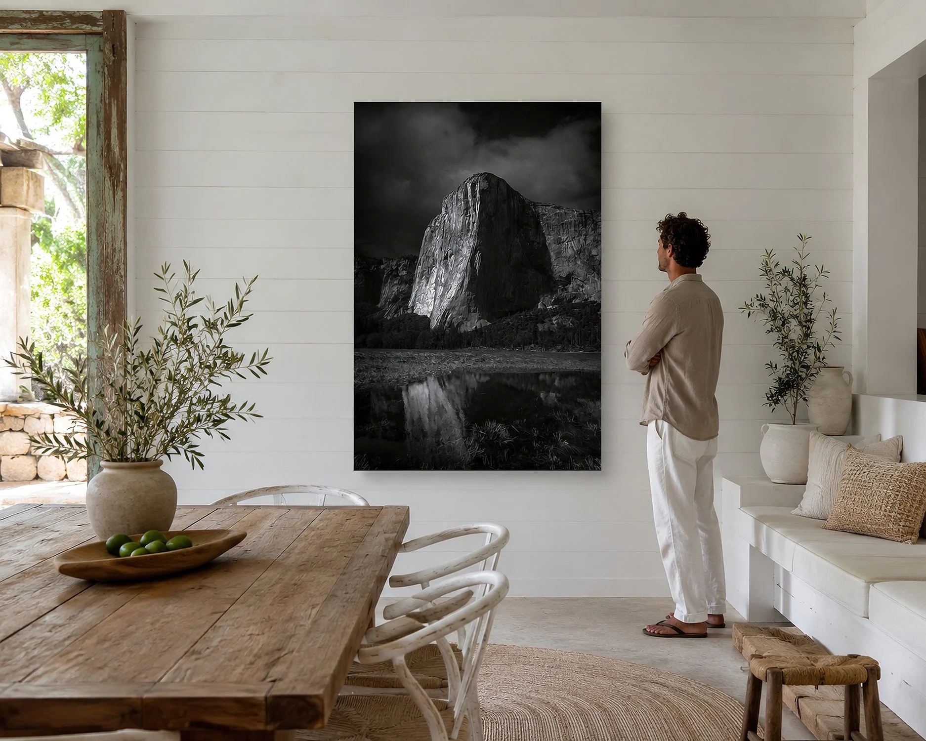 Black-and-white El Capitan photograph displayed in a bright farmhouse dining room with a man standing nearby.