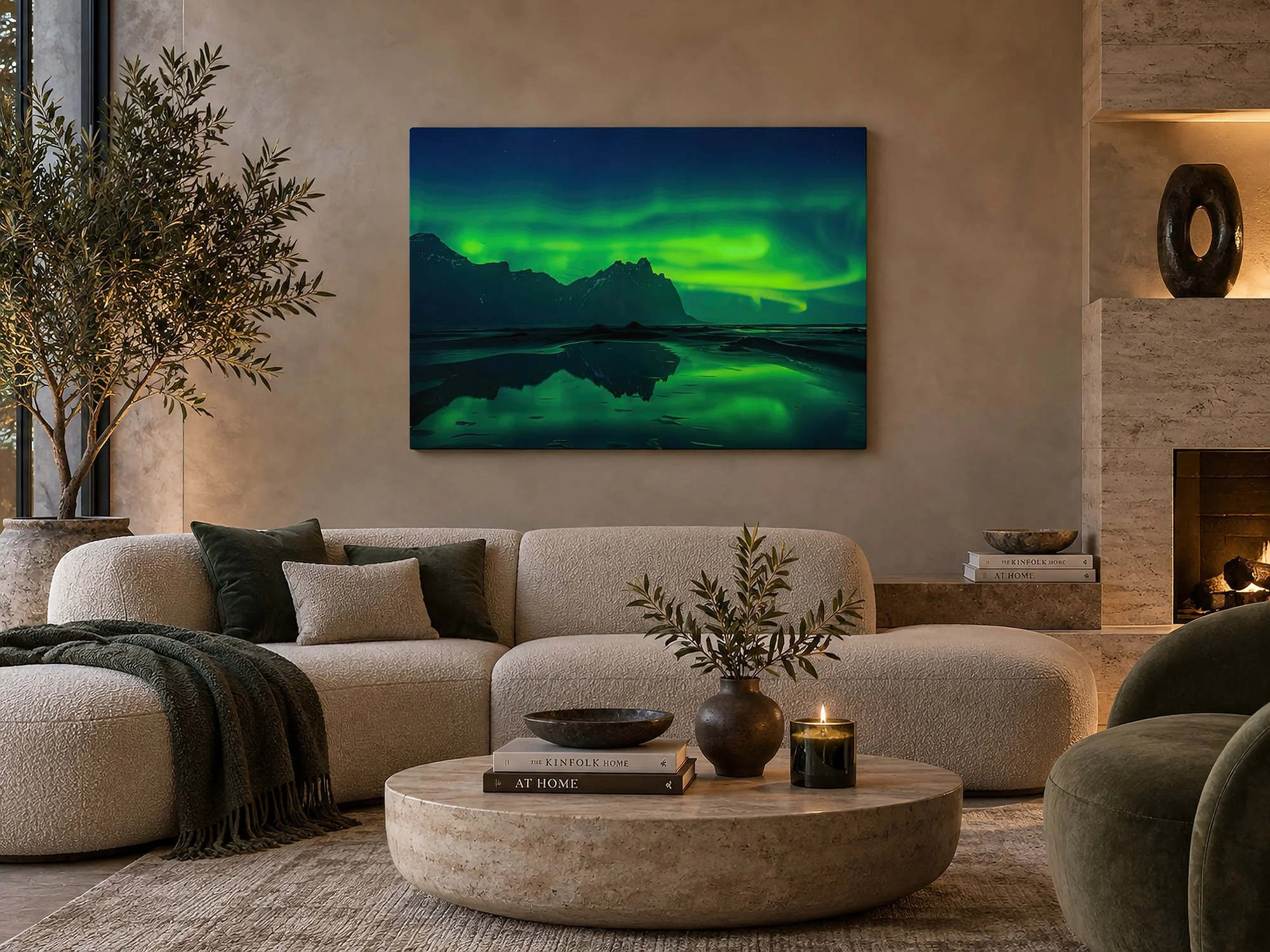 Warm contemporary lounge with curved neutral seating, stone coffee table and fireplace, featuring an 80 x 60 cm canvas print of glowing green aurora above a dark mountain range reflected in still water by Nick Psomiadis at NIKART Studio and Gallery
