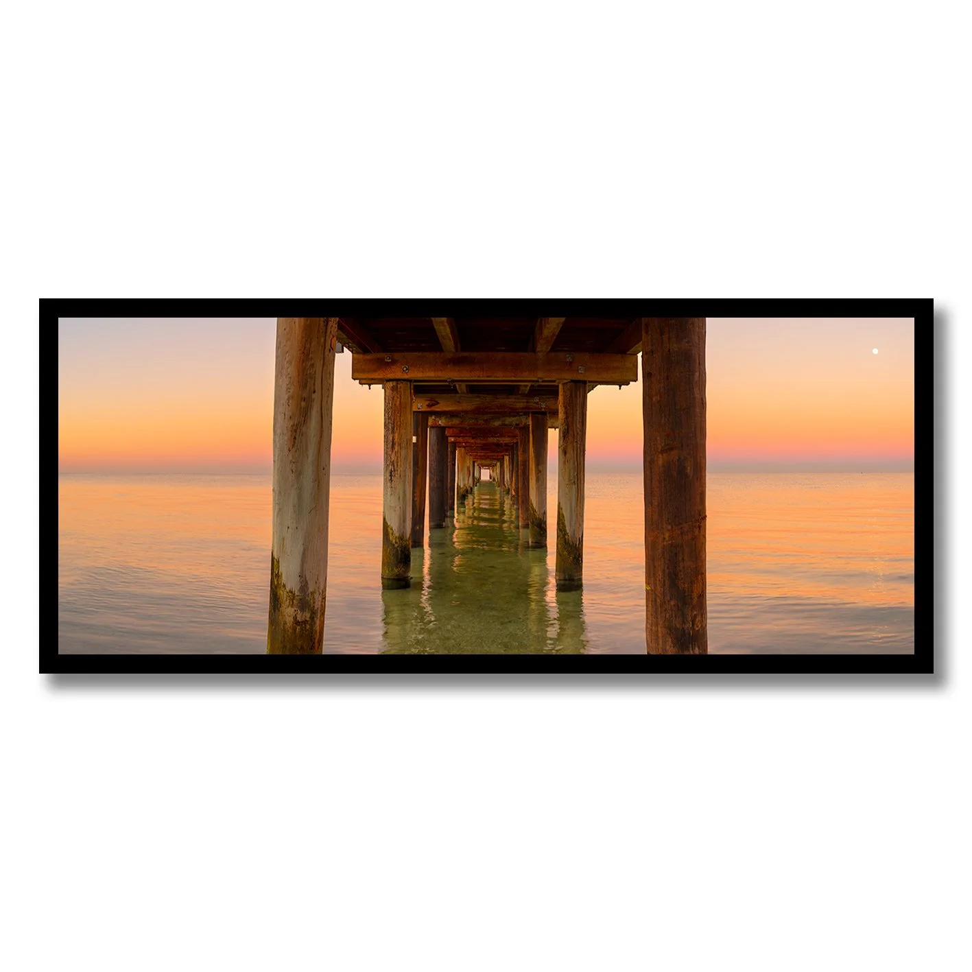 fine art photograph looking under seaford pier at sunset with calm reflective water