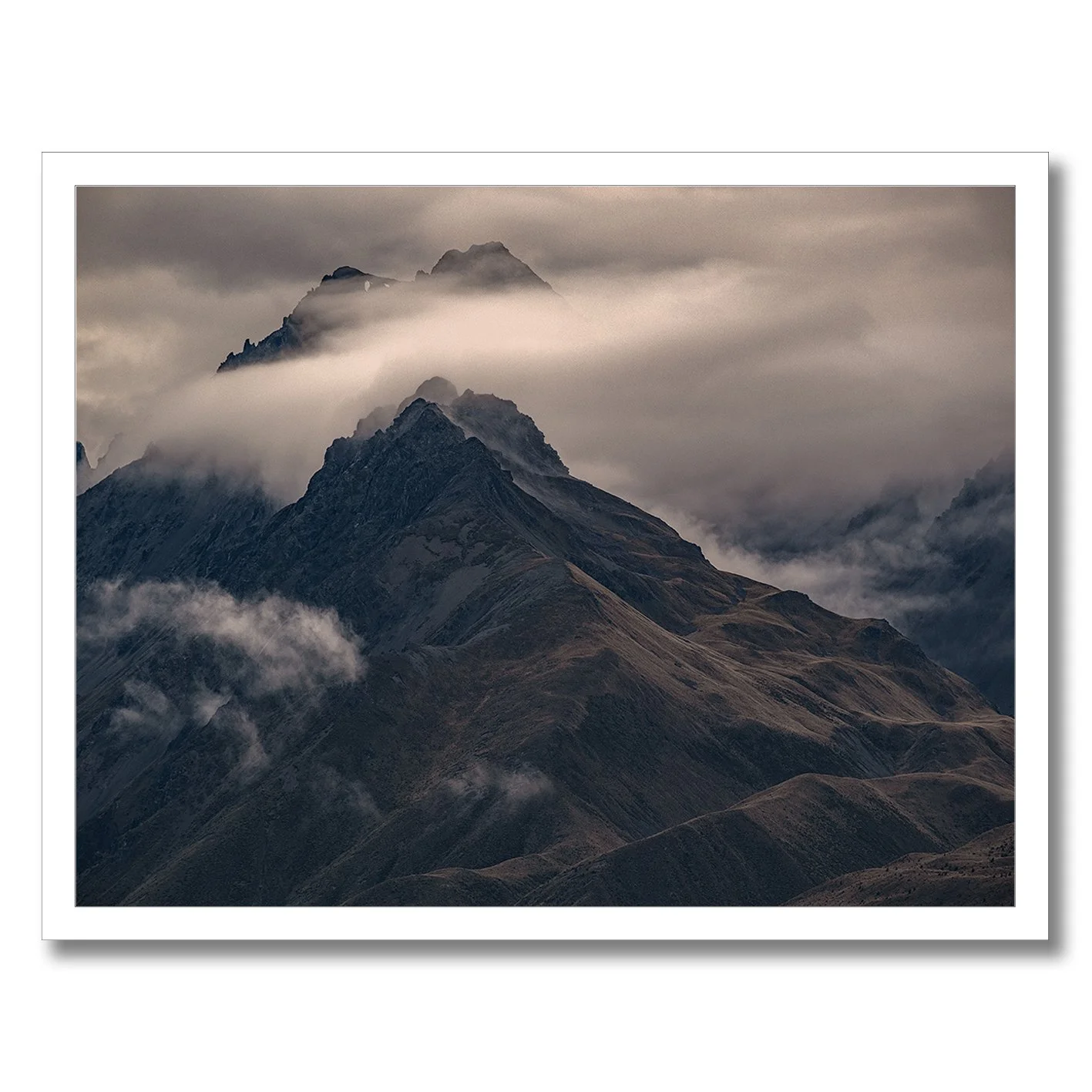 Moody mountain photograph with mist drifting across dark alpine ridges