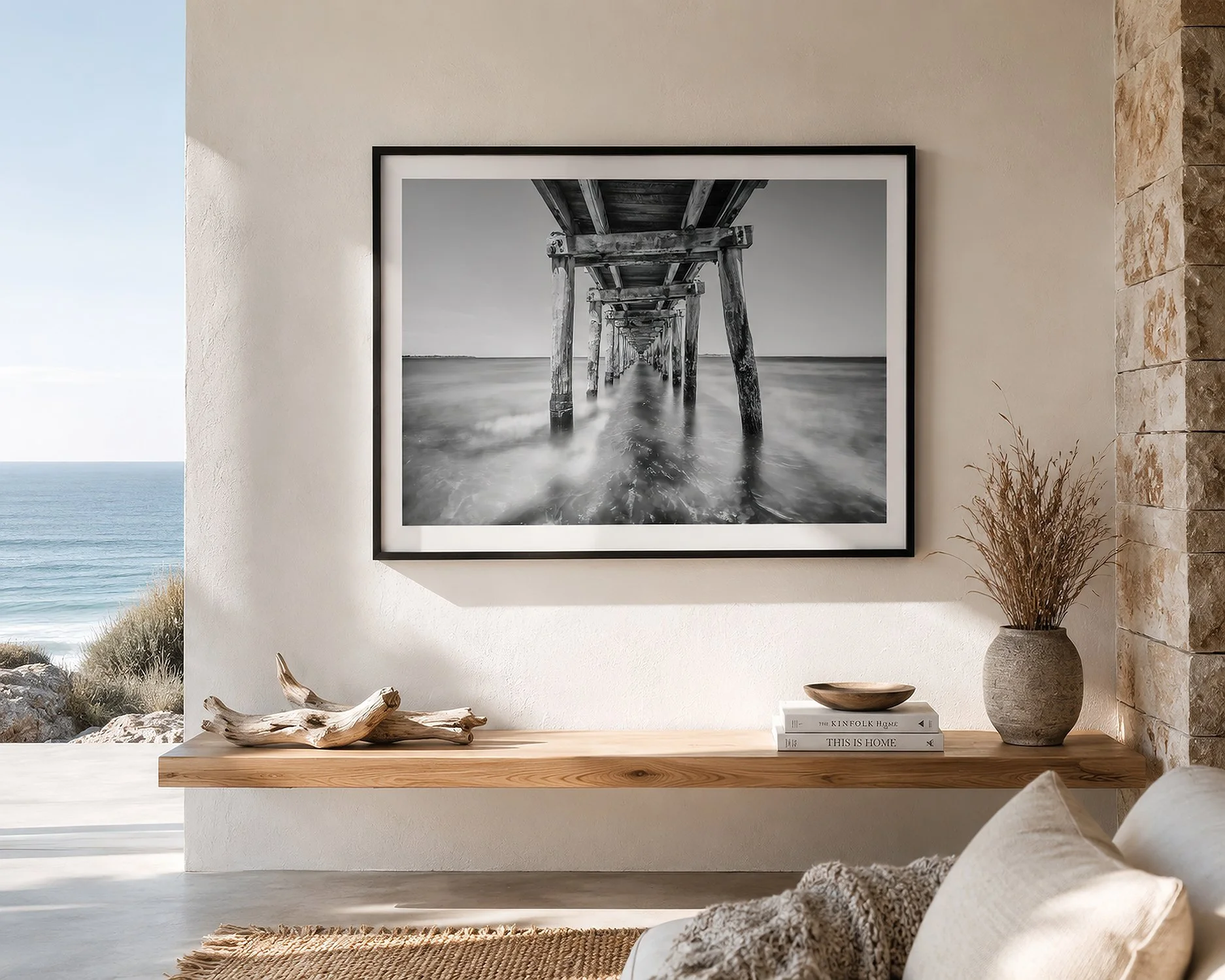 Bright coastal interior featuring a framed black and white photograph beneath Point Lonsdale Pier, styled with natural timber, stone textures and ocean views, by Nick Psomiadis at NIKART Studio and Gallery.