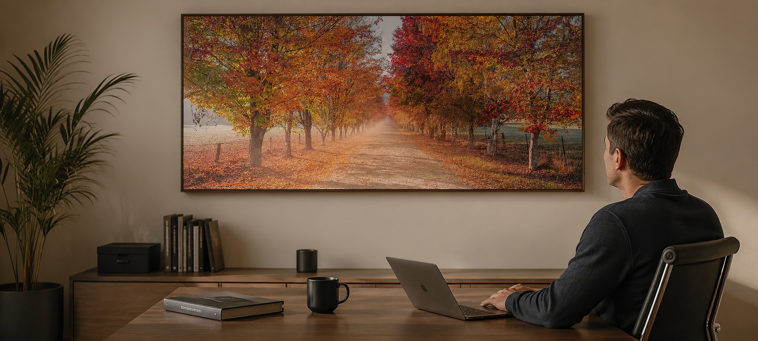 Modern office interior with a seated man facing a large framed autumn landscape photograph above a timber desk, by Nick Psomiadis at NIKART Studio and Gallery.