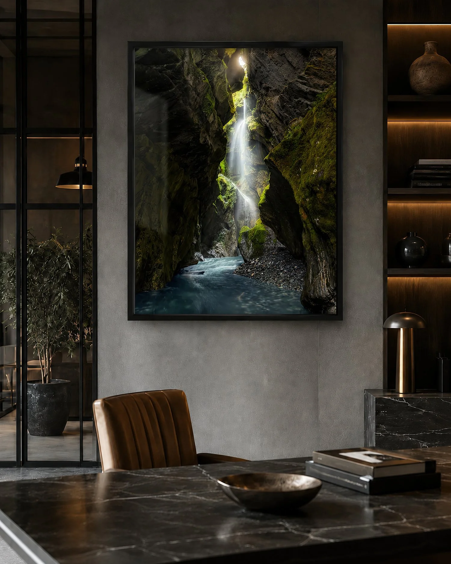 Black-framed canyon waterfall photograph displayed in a moody modern office with dark shelving, marble desk and warm ambient lighting by Nick Psomiadis at NIKART Studio and Gallery