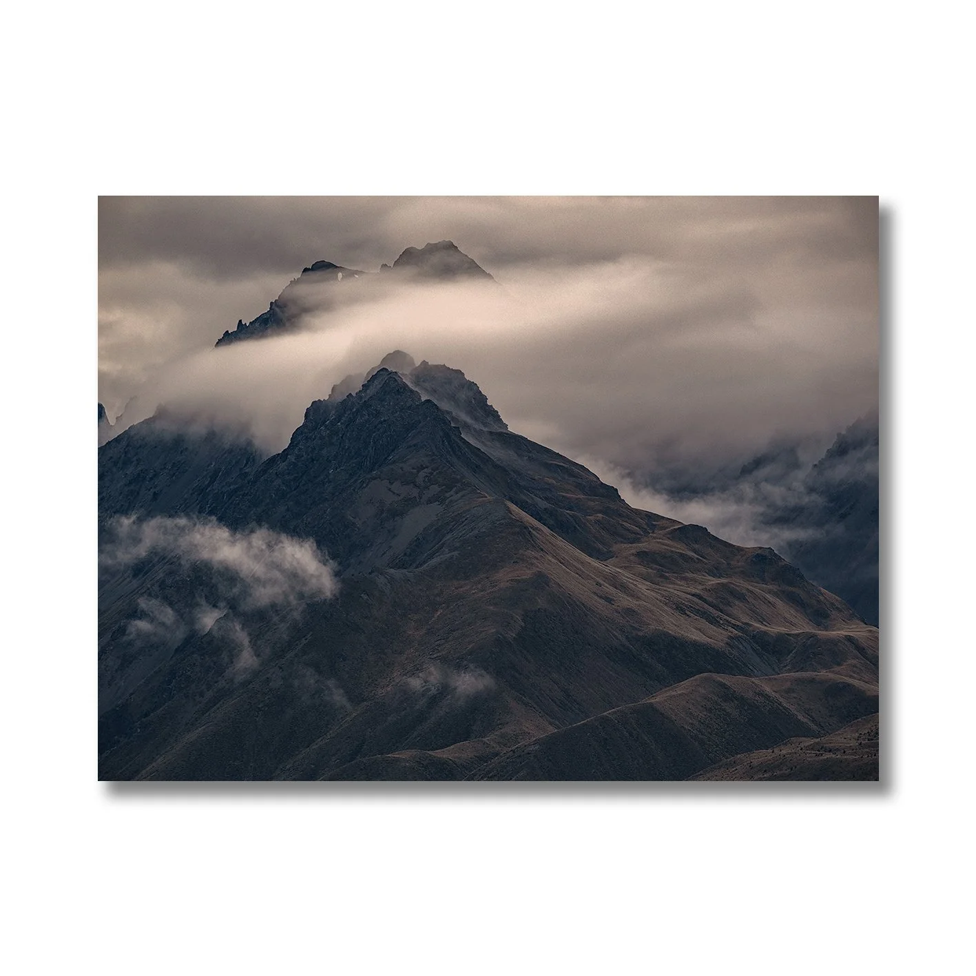 Moody mountain photograph with mist drifting across dark alpine ridges