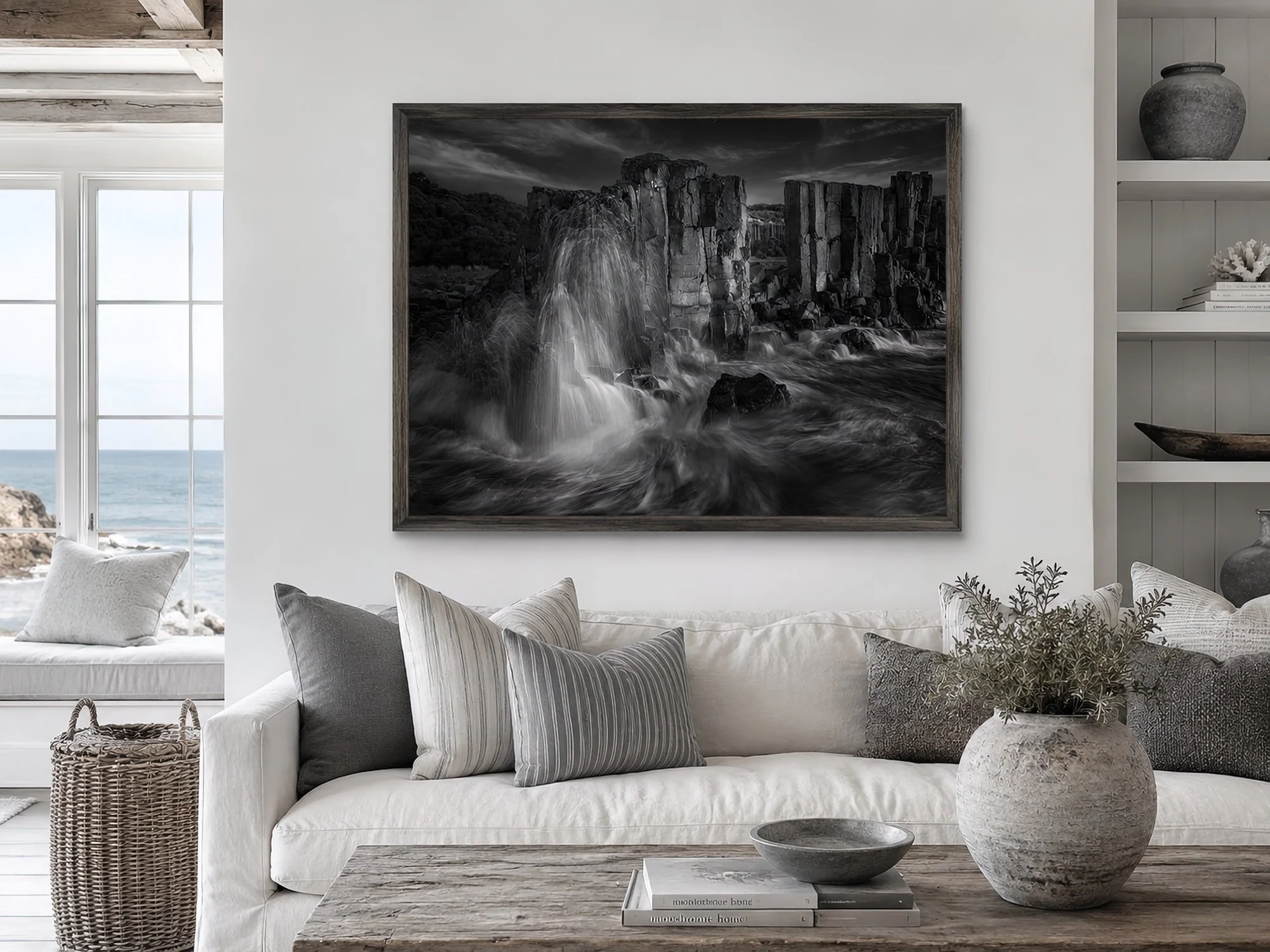 Monochrome coastal living room with a framed Bombo Quarry waterfall photograph above a white sofa by Nick Psomiadis at NIKART Studio and Gallery