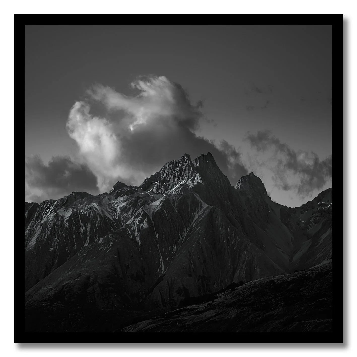 black and white mountain peak under dramatic clouds photograph