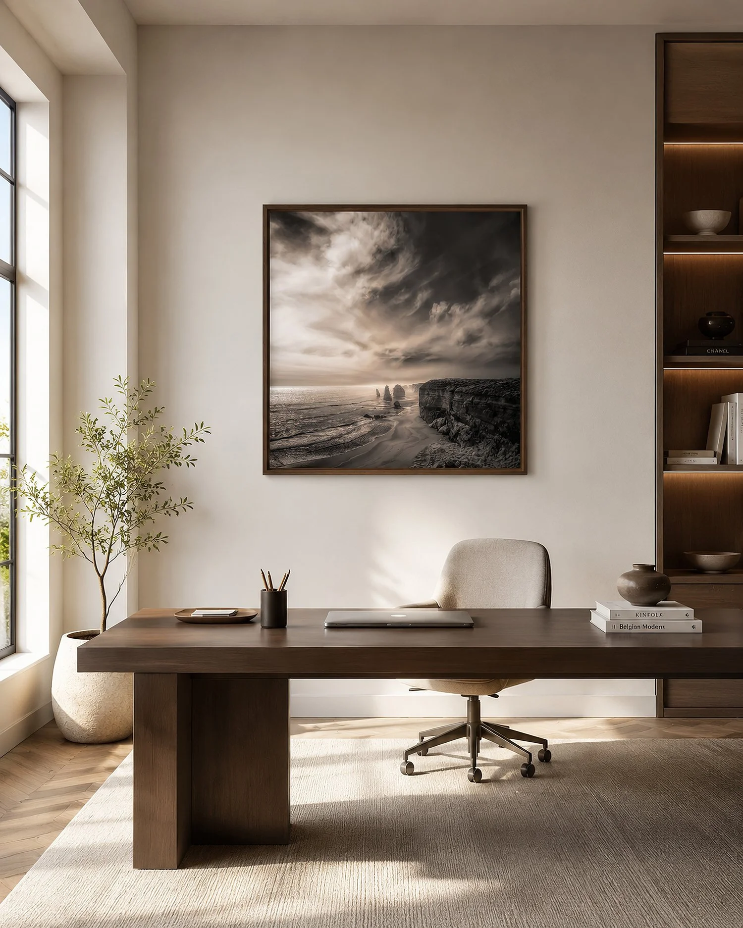 Square framed photograph of the Twelve Apostles in a dark timber frame, displayed above a desk in a naturally lit minimalist office, by Nick Psomiadis at NIKART Studio and Gallery