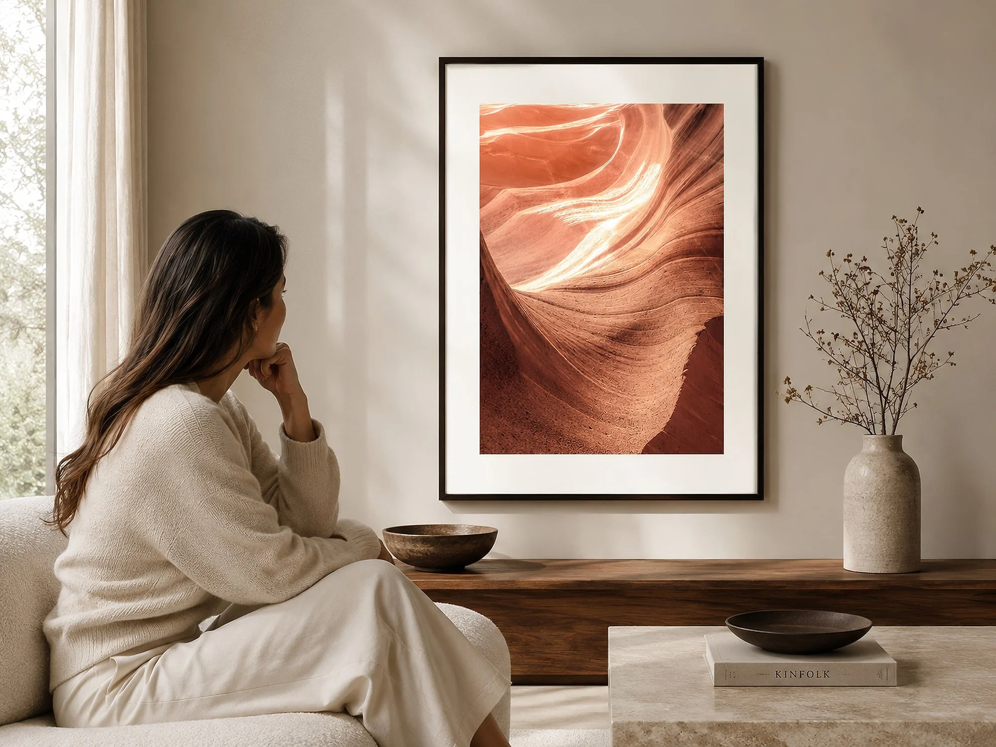Framed Antelope Canyon photograph with an even white border displayed in a soft neutral living room with a seated woman.