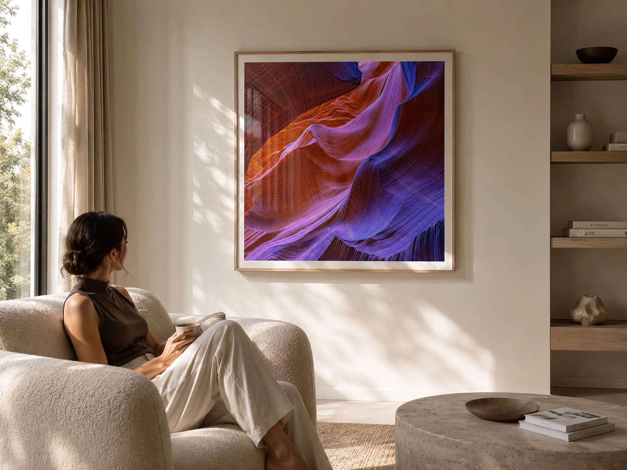 Bright minimalist living room with a seated woman beside a timber-framed colourful Antelope Canyon photograph with natural glass reflections by Nick Psomiadis at NIKART Studio and Gallery