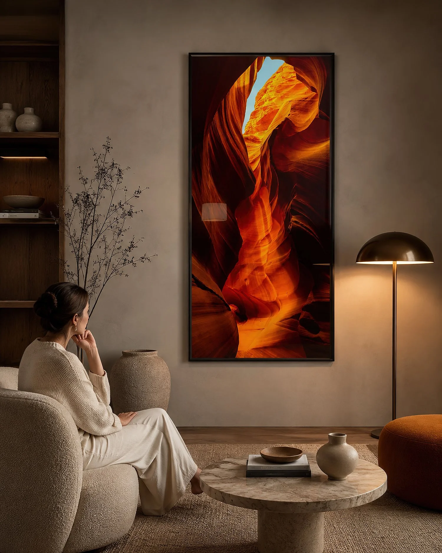 Framed Antelope Canyon photograph with glowing orange sandstone curves in a warm minimalist living room with a seated woman, by Nick Psomiadis at NIKART Studio and Gallery