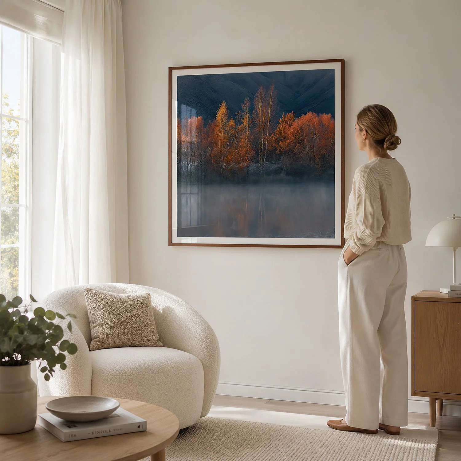 Bright neutral reading room with a woman viewing a square autumn landscape photograph in a walnut frame by Nick Psomiadis at NIKART Studio and Gallery