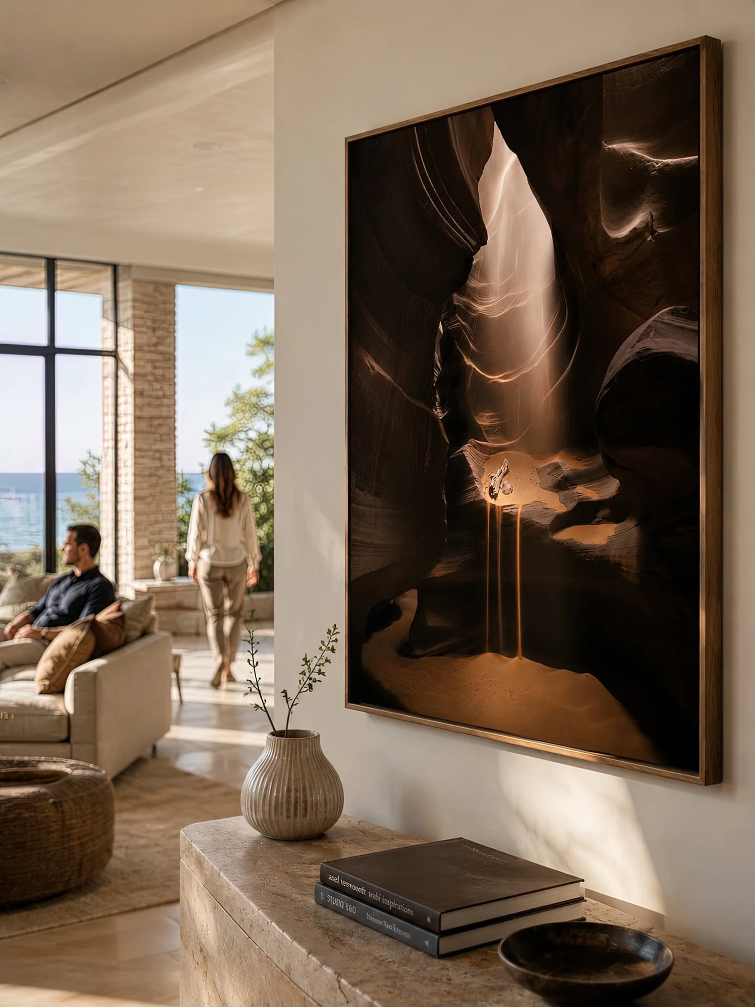 Close-up of a timber-framed Antelope Canyon sandfall photograph in a bright living room with a seated man and walking woman by Nick Psomiadis at NIKART Studio and Gallery