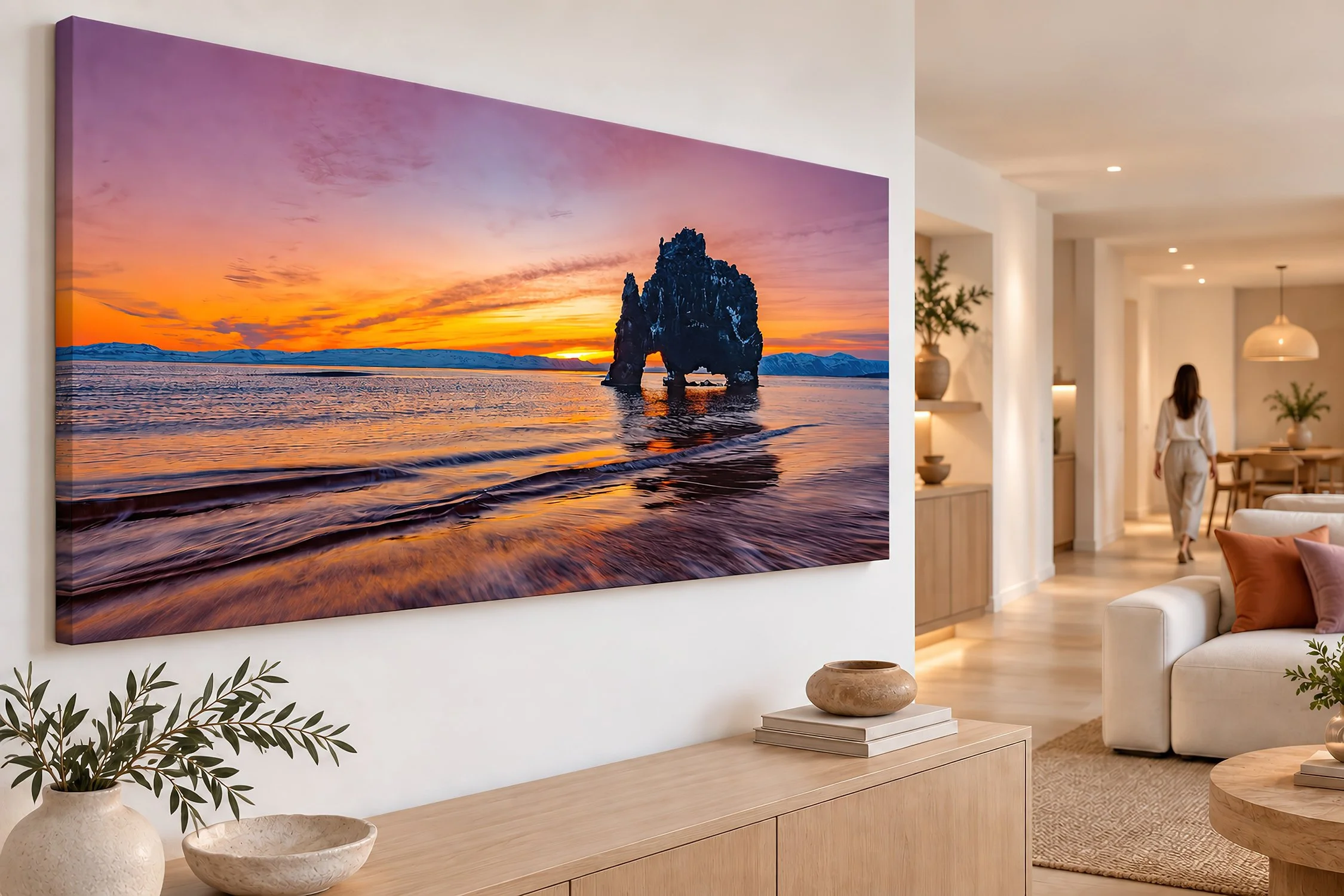 Large sunset photograph of Iceland's dramatic sea arch above a timber sideboard in a modern living room by Nick Psomiadis at NIKART Studio and Gallery