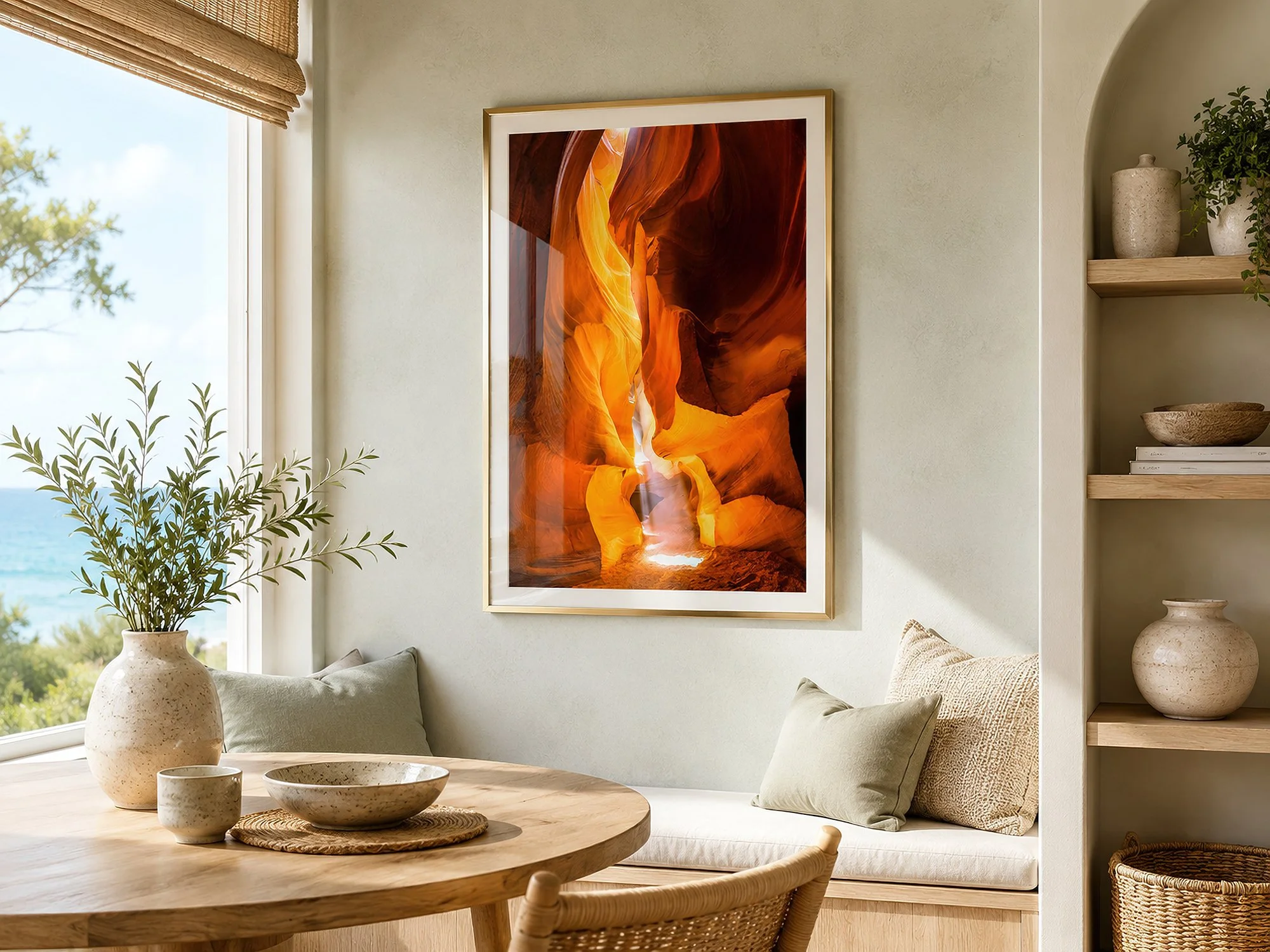 Framed Antelope Canyon photograph displayed behind subtly reflective glass in a bright coastal dining nook with pale timber furnishings, built-in seating and ocean views — Nick Psomiadis at NIKART Studio and Gallery.