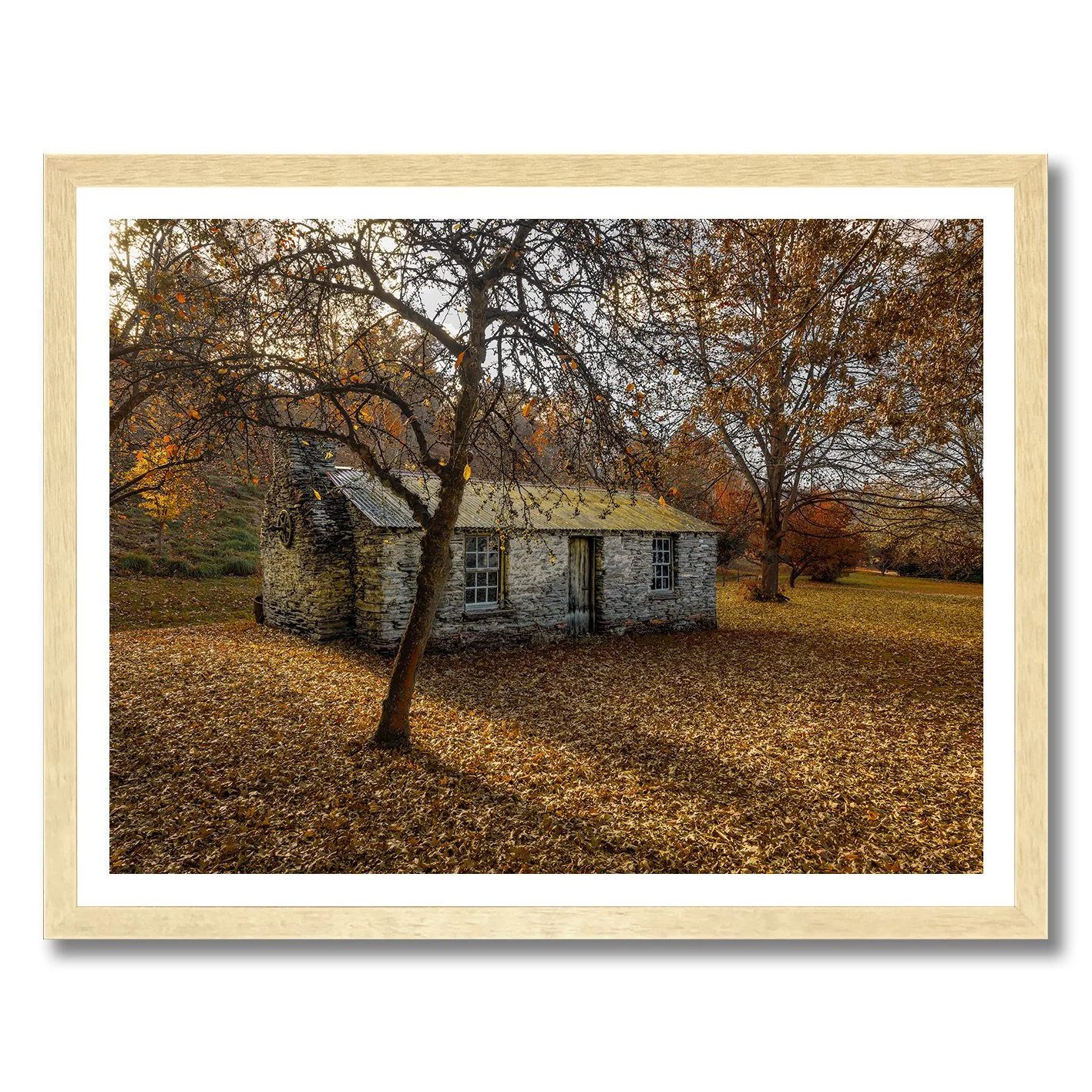 Stone cottage surrounded by autumn leaves and trees in a rural landscape photograph
