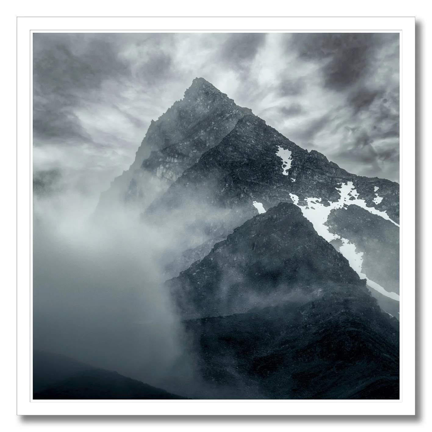 Mountain photograph emerging through mist and cloud with rugged alpine peak