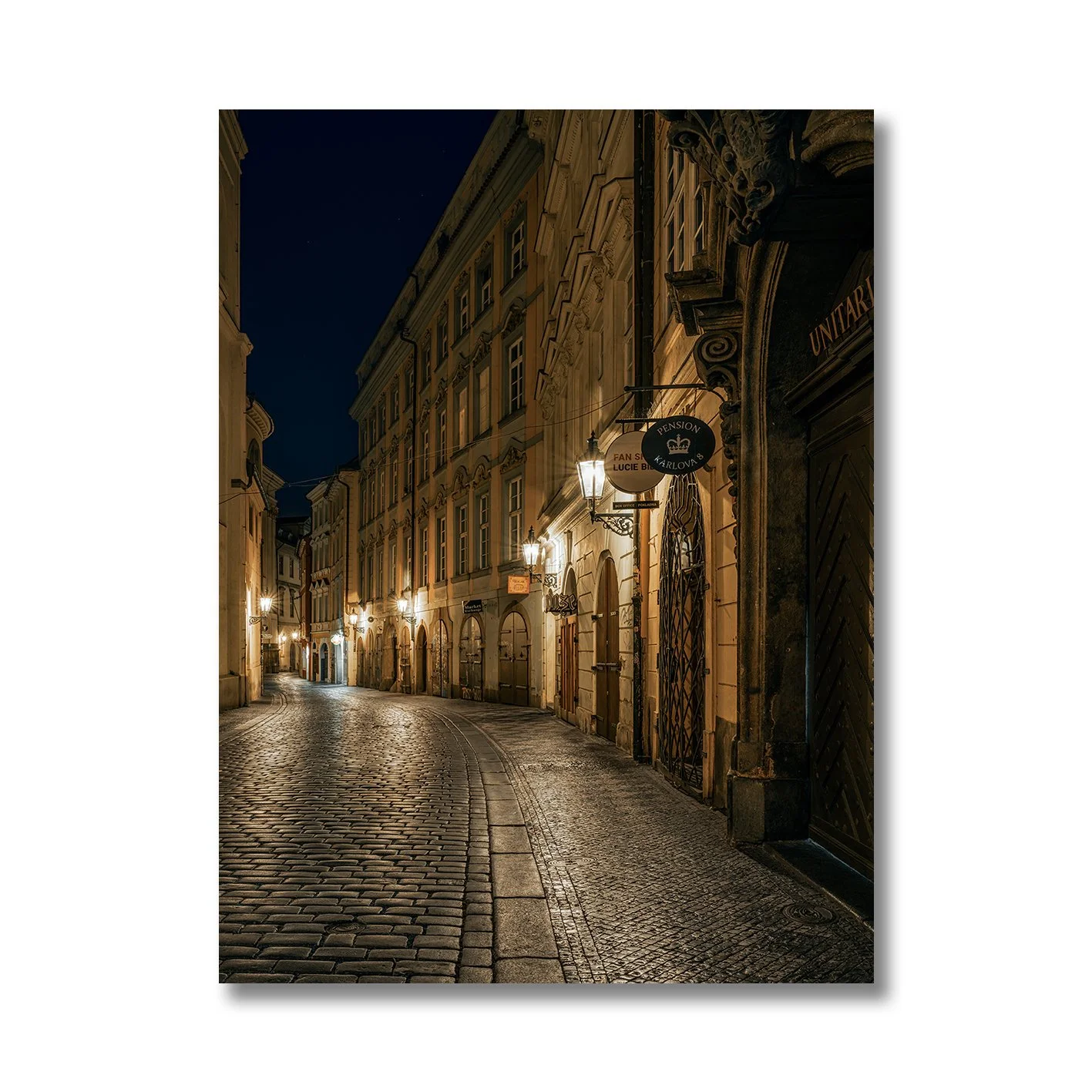 Night photograph of a quiet cobblestone street in Prague with warm lamps
