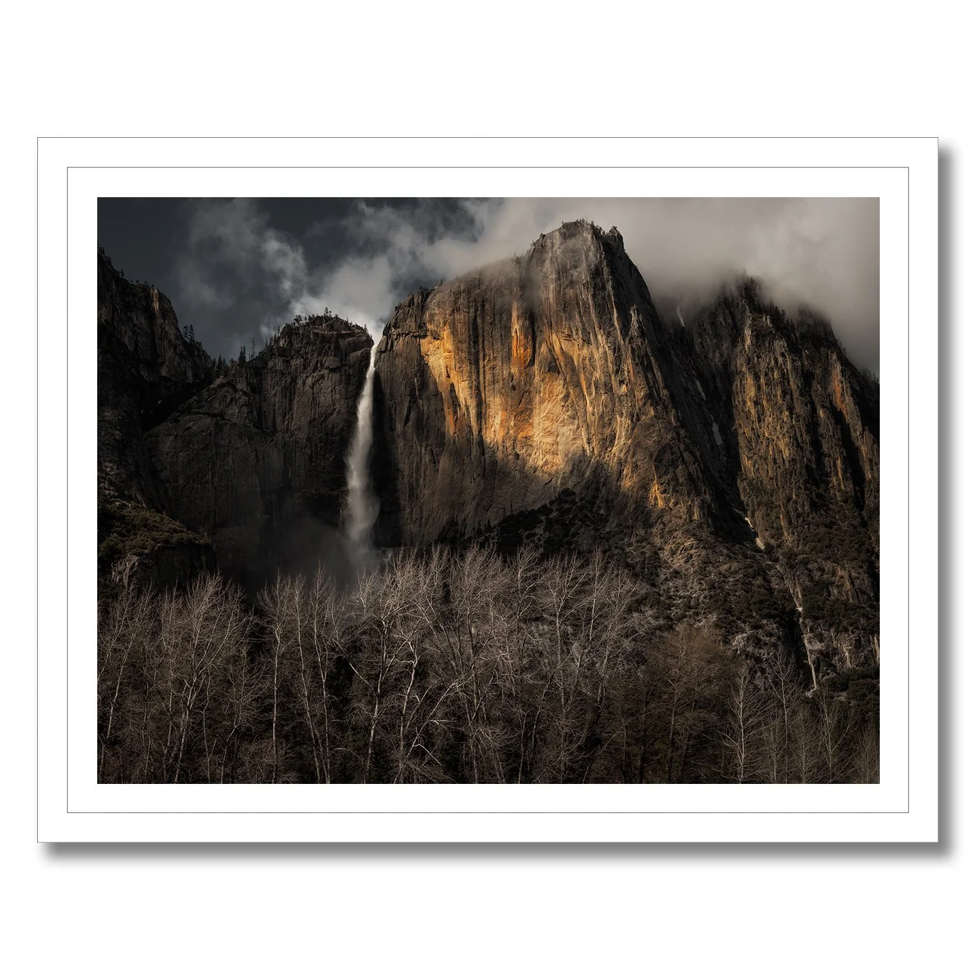 Yosemite Falls photograph with sunlit granite cliffs, mist and dark woodland in California