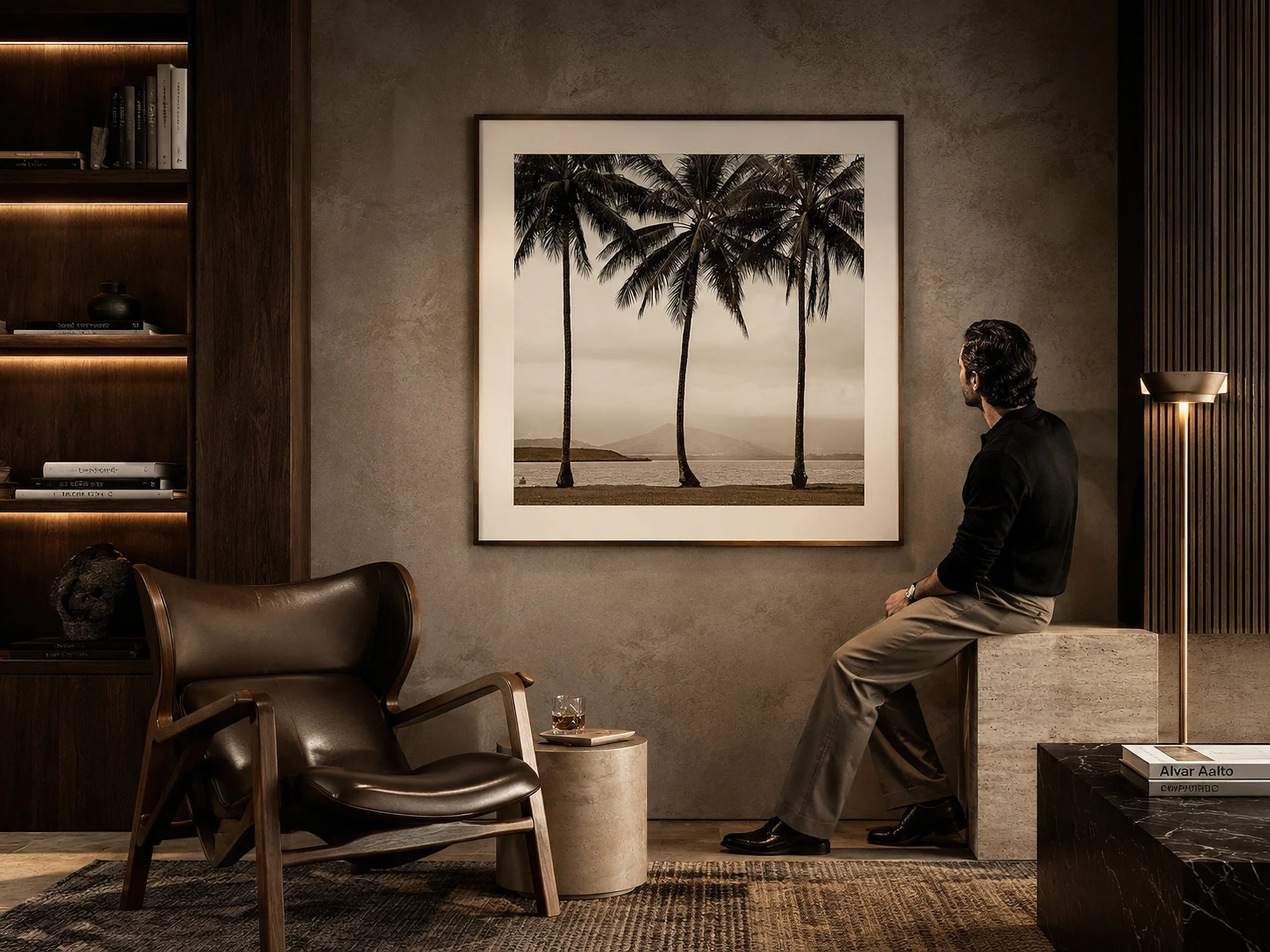 Framed monochrome palm tree photograph displayed in a moody luxury interior with a man seated nearby.