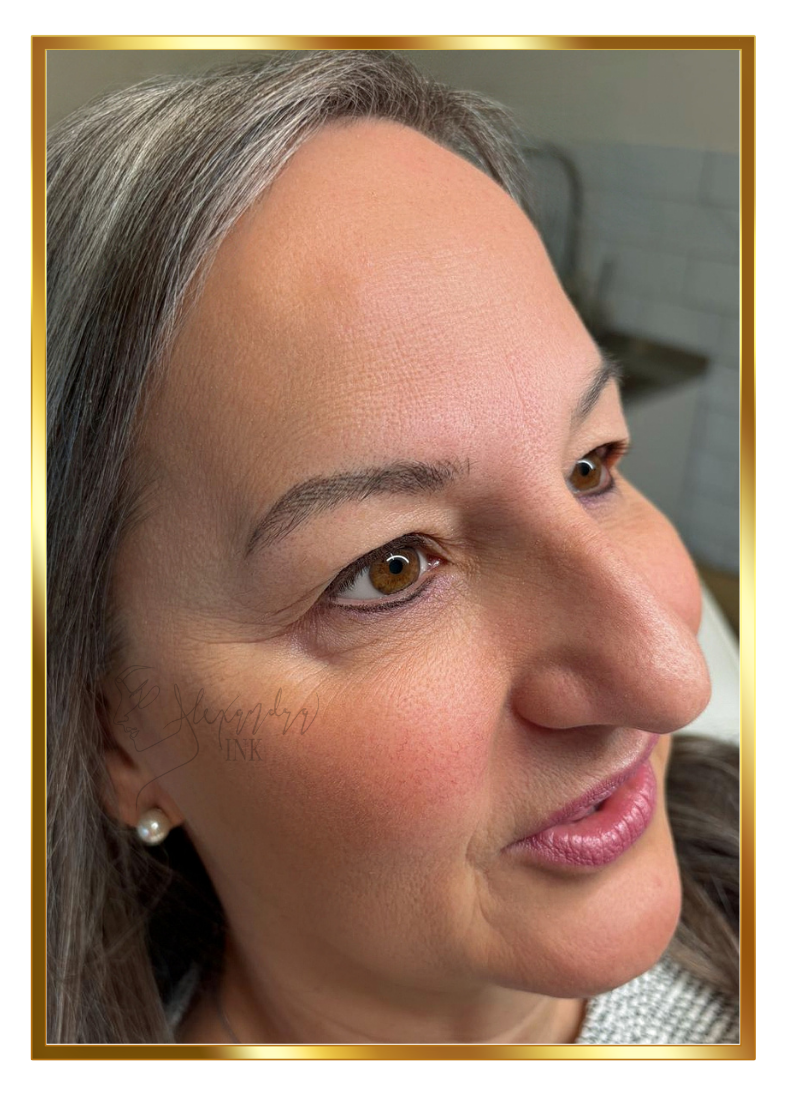 Close-up of a smiling woman with gray hair, light skin, brown eyes, wearing pearl earrings, looking to the side, with a blurred background.